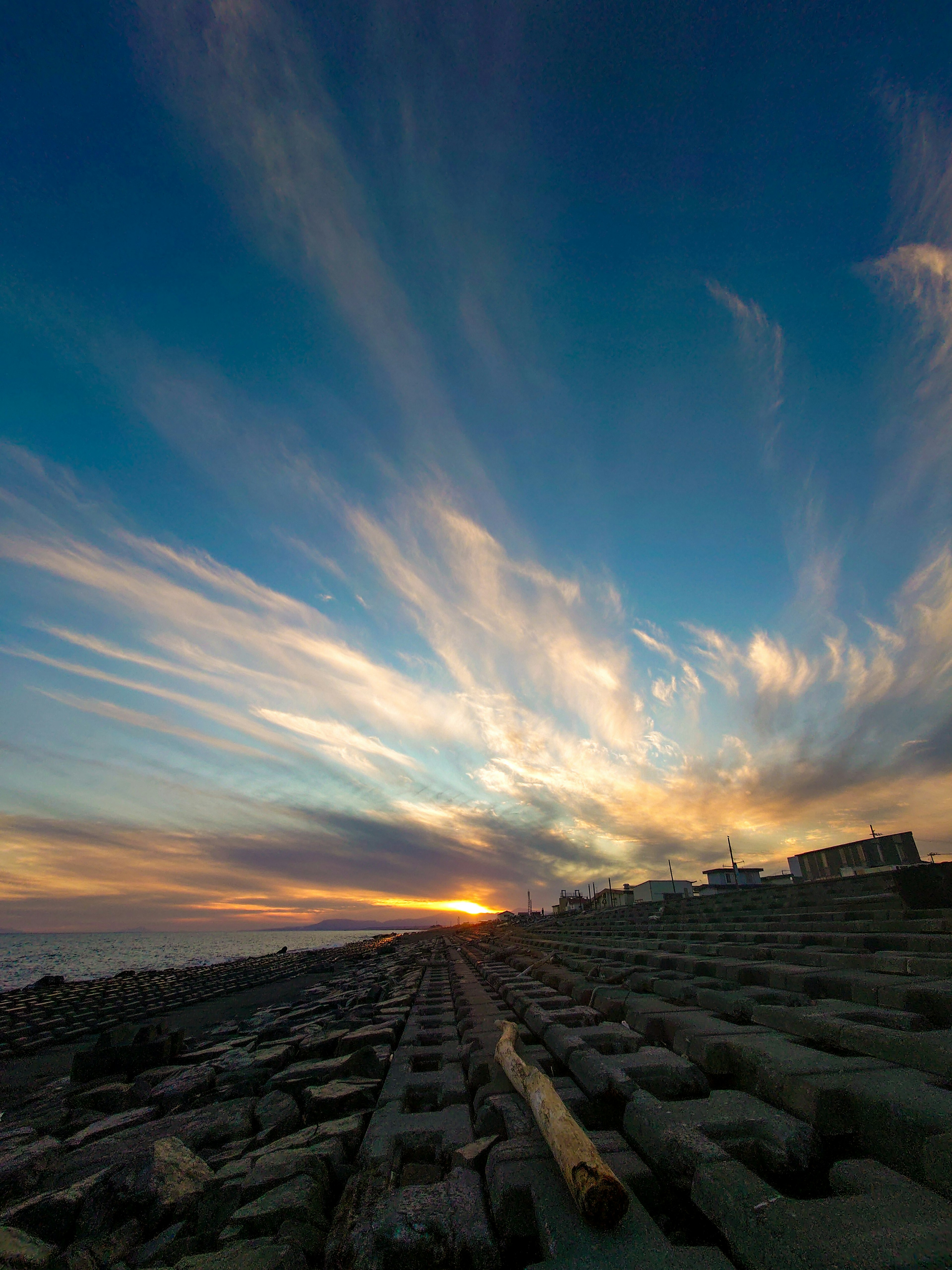 Stunning sunset sky with colorful clouds and wooden beams along the shoreline