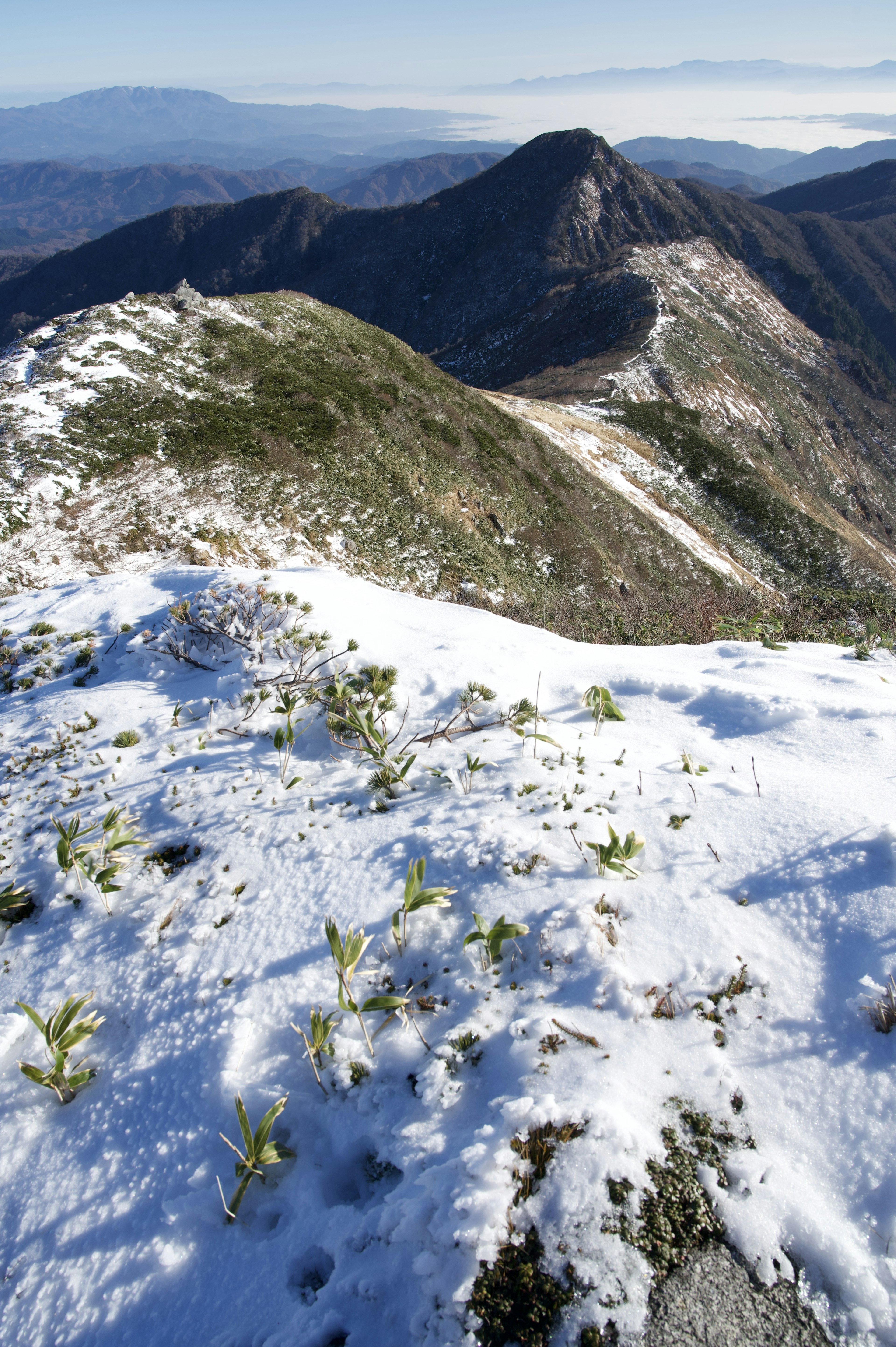 雪に覆われた山の頂上の風景 緑の草がちらほら見える