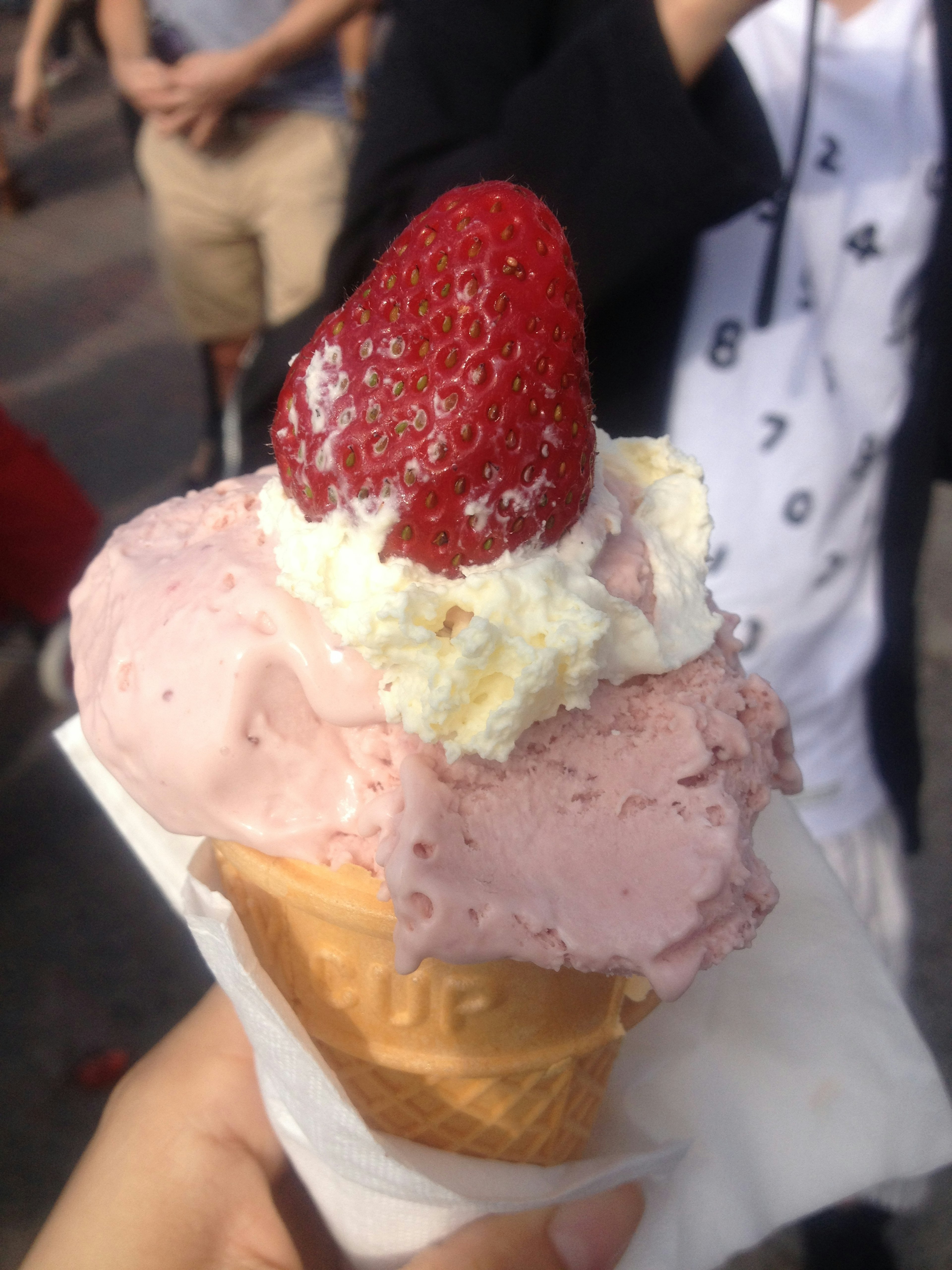 Ice cream cone topped with strawberry and whipped cream