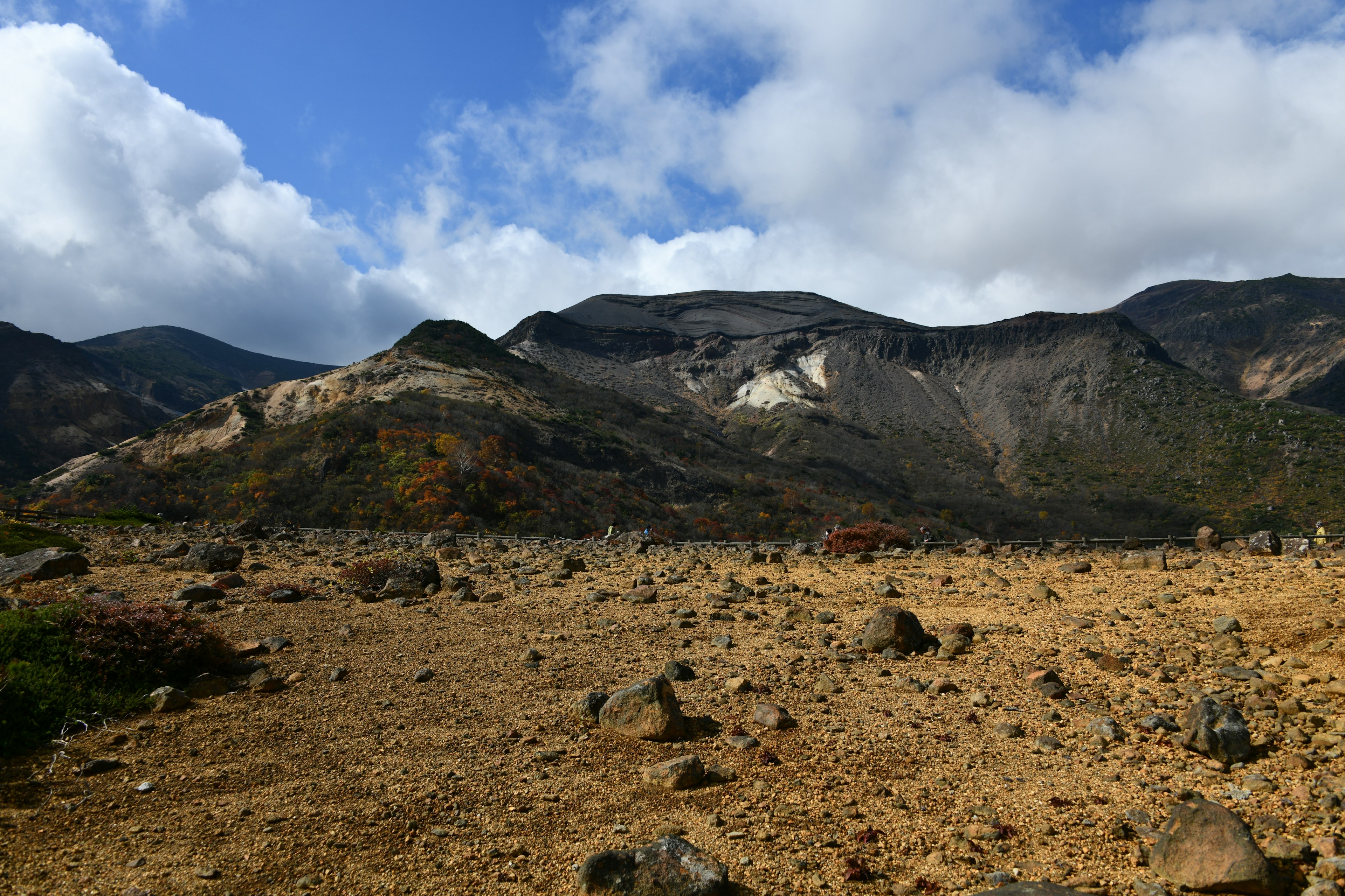 Trockene Landschaft mit verstreuten Steinen und Bergen blauer Himmel mit weißen Wolken