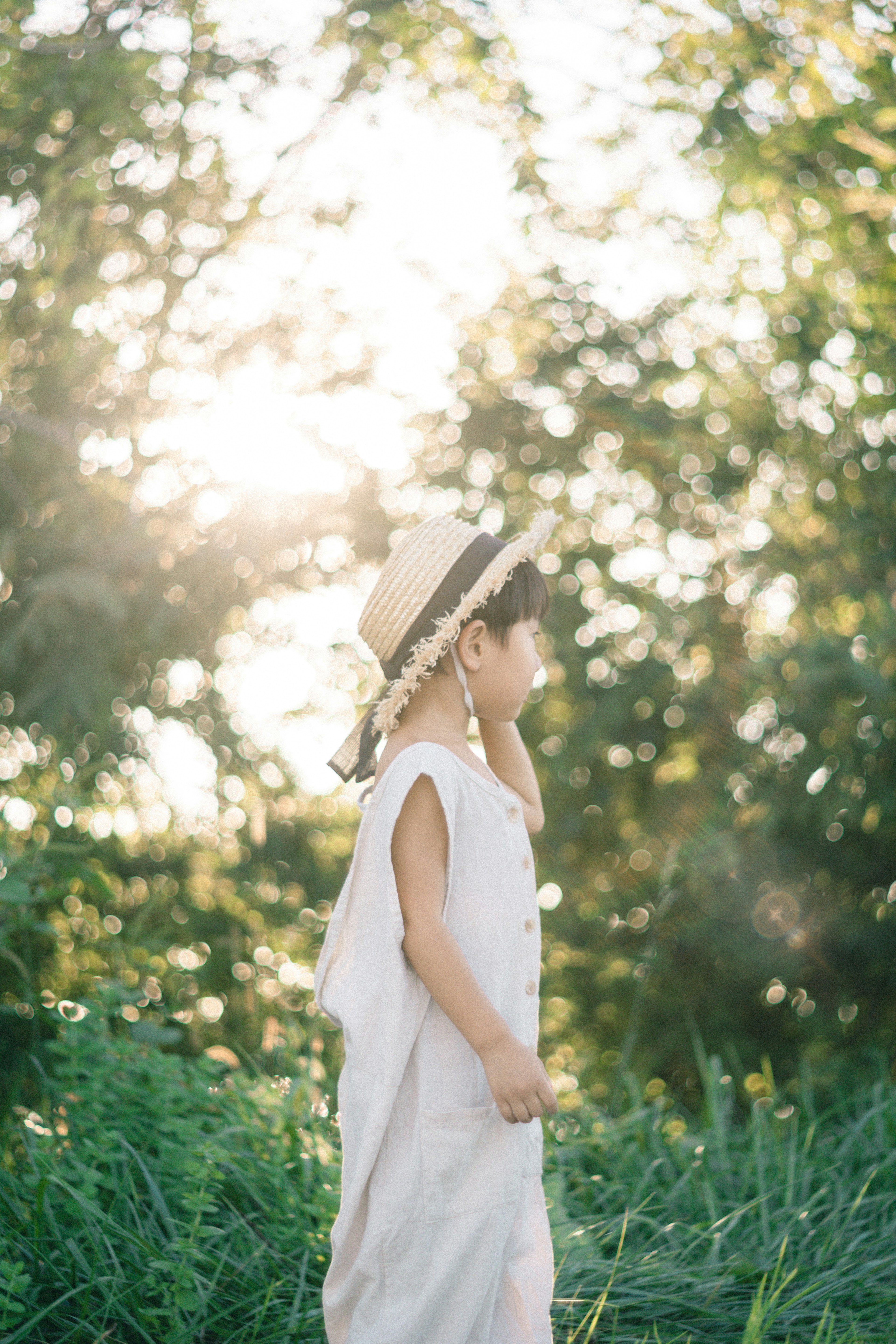 A child wearing a straw hat walking through green grass