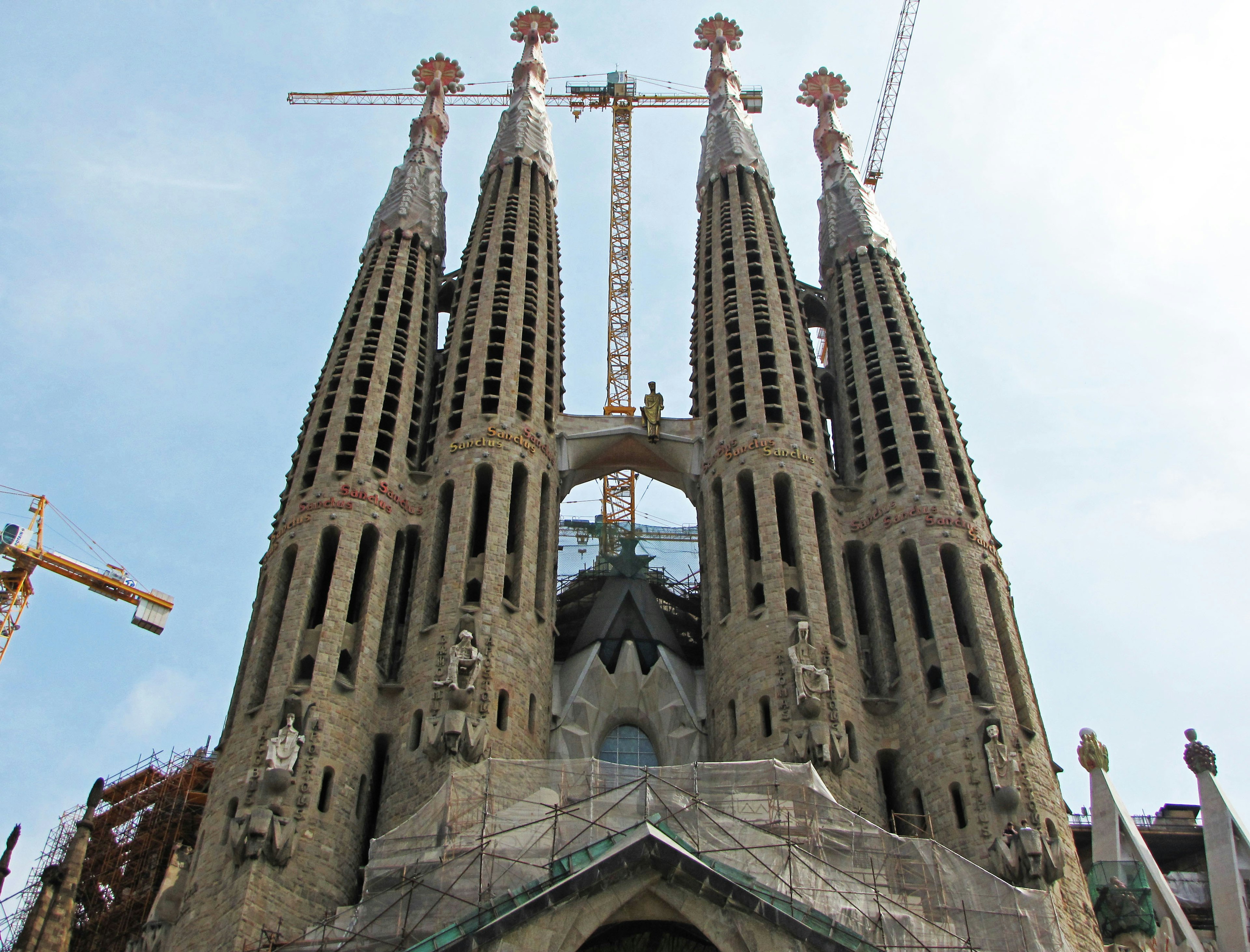 Façade en construction de la Sagrada Familia avec des flèches