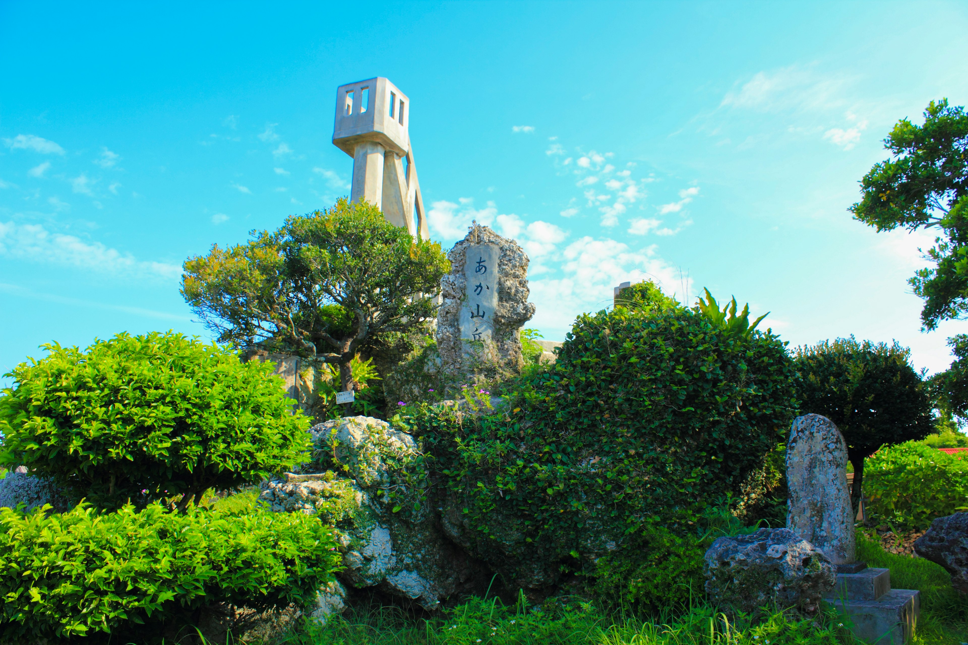 Eine malerische Ansicht eines Turms, umgeben von üppigem Grün unter einem blauen Himmel