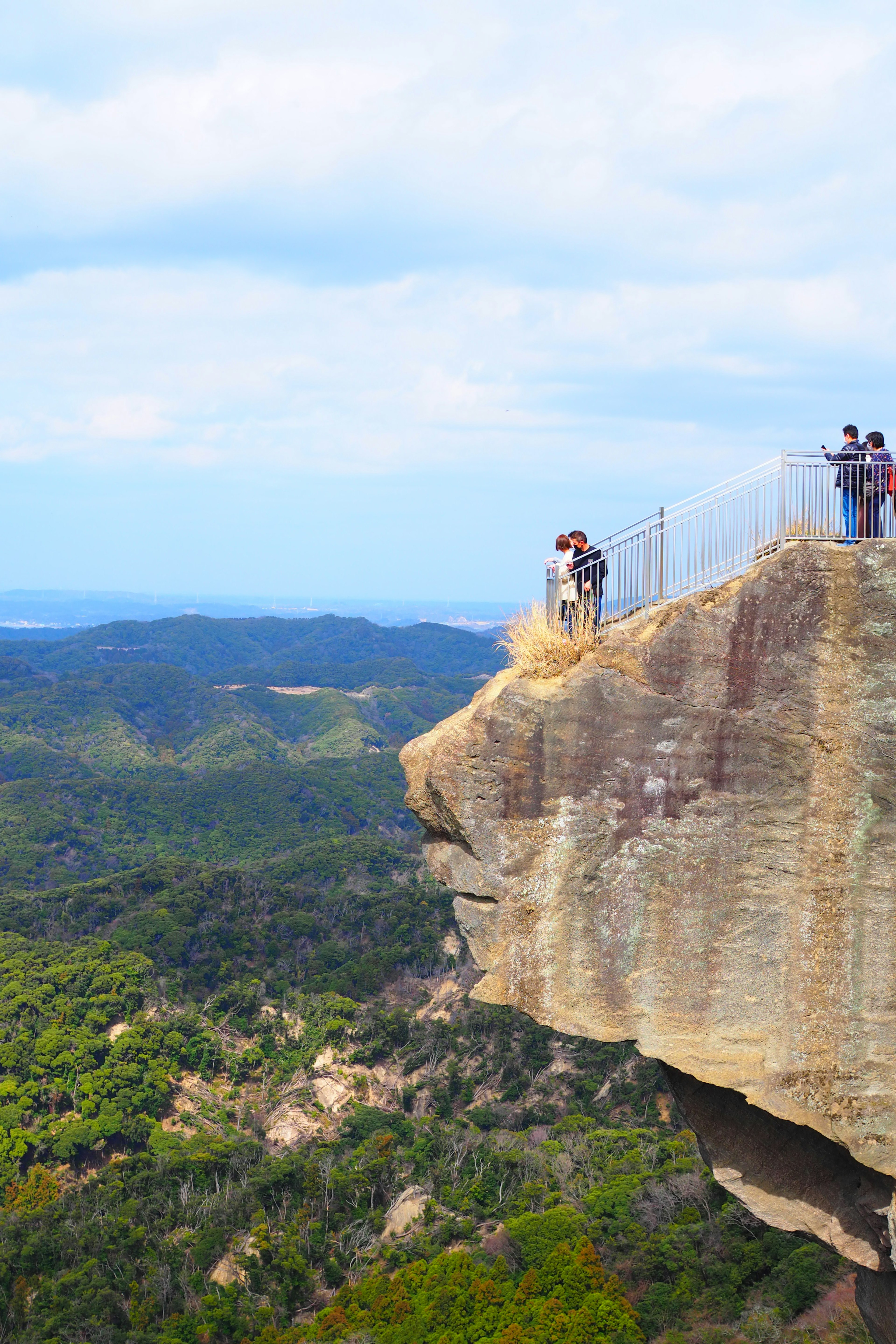 People standing on the edge of a cliff with beautiful mountains in the background