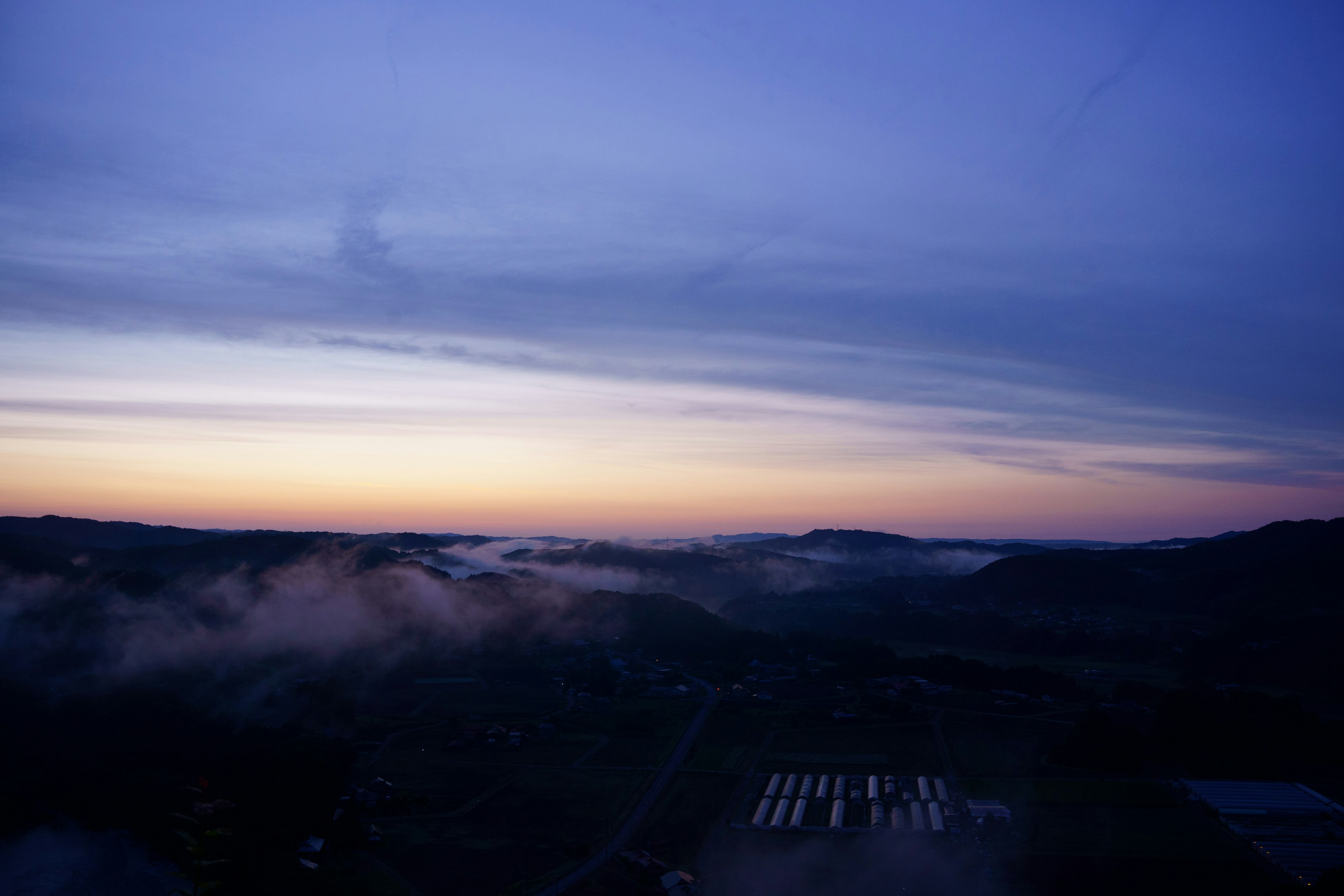 A scenic view of a purple sky with dawn light and clouds