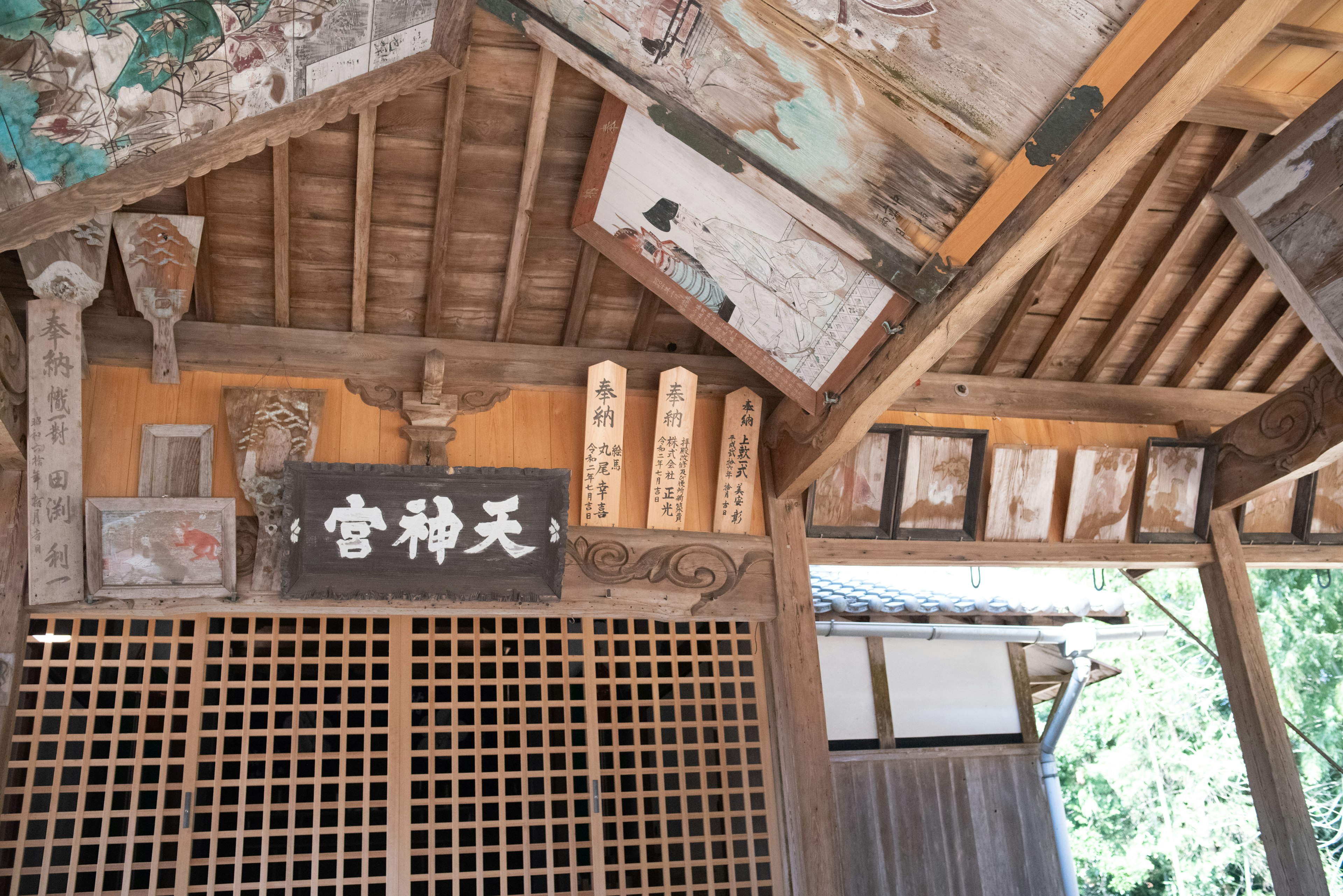 Interior of a traditional Japanese shrine featuring wooden beams and hanging artwork