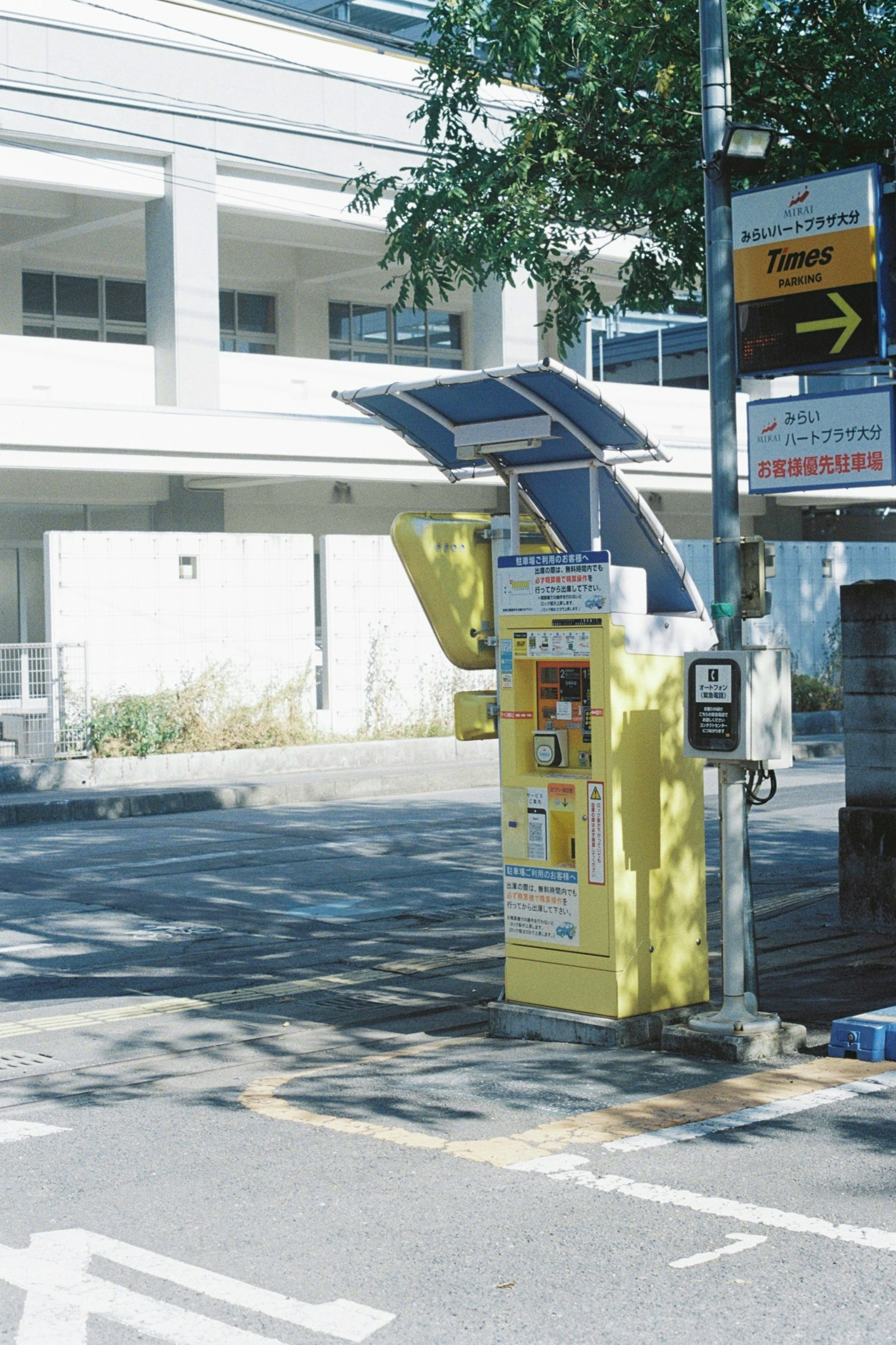 Bright yellow vending machine with solar panel and surrounding street scene