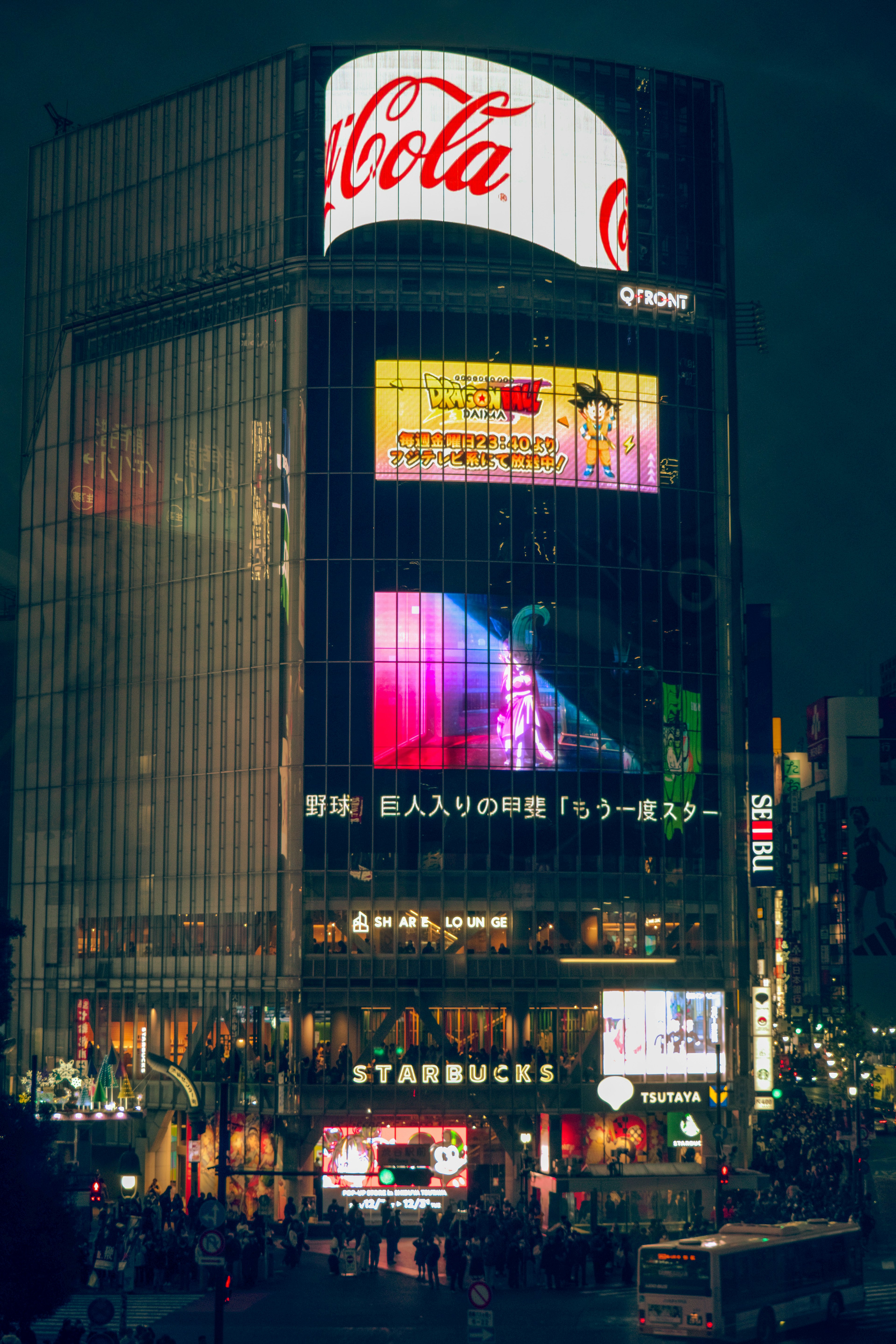 Shibuya di notte con un'insegna Coca-Cola luminosa e pubblicità colorate su un edificio