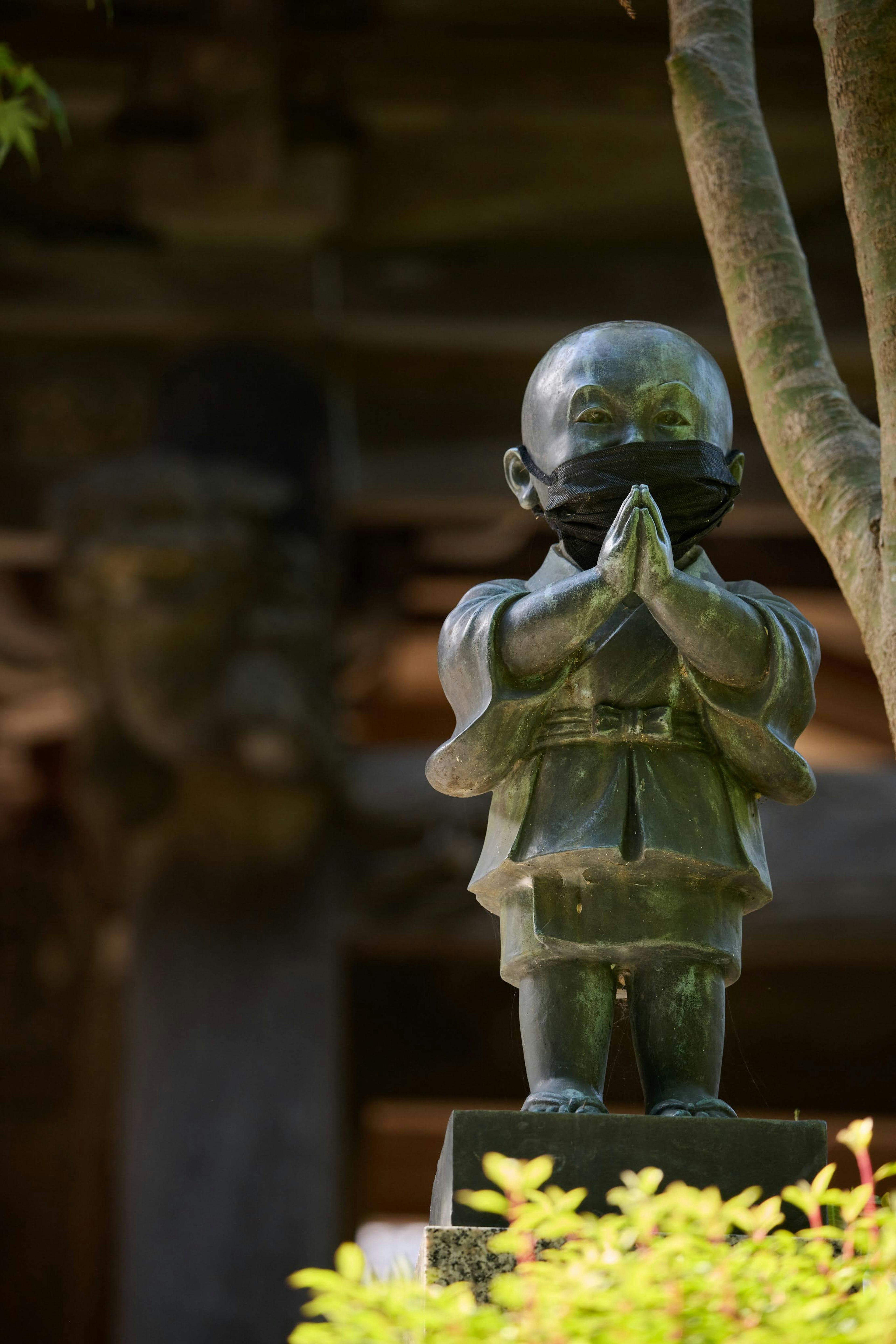 Statue d'enfant les mains en prière entourée de verdure