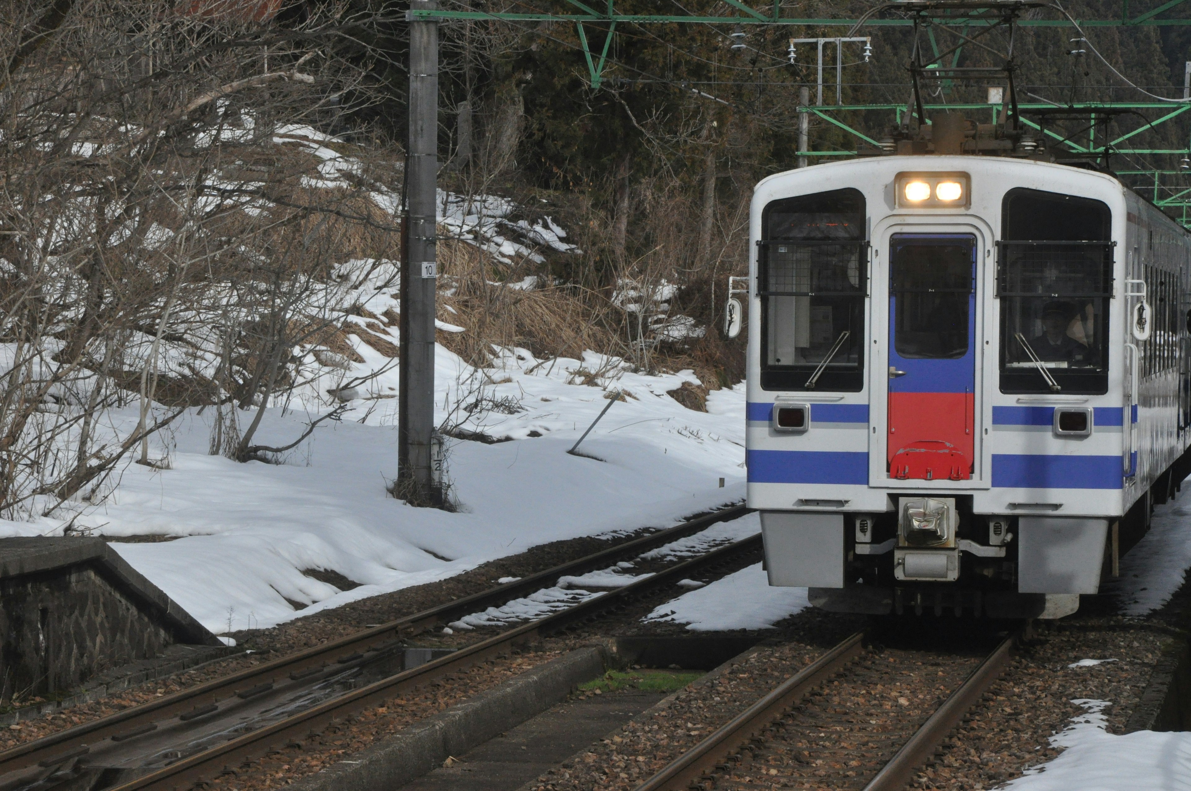 Tren acercándose por vías nevadas con paisaje invernal alrededor