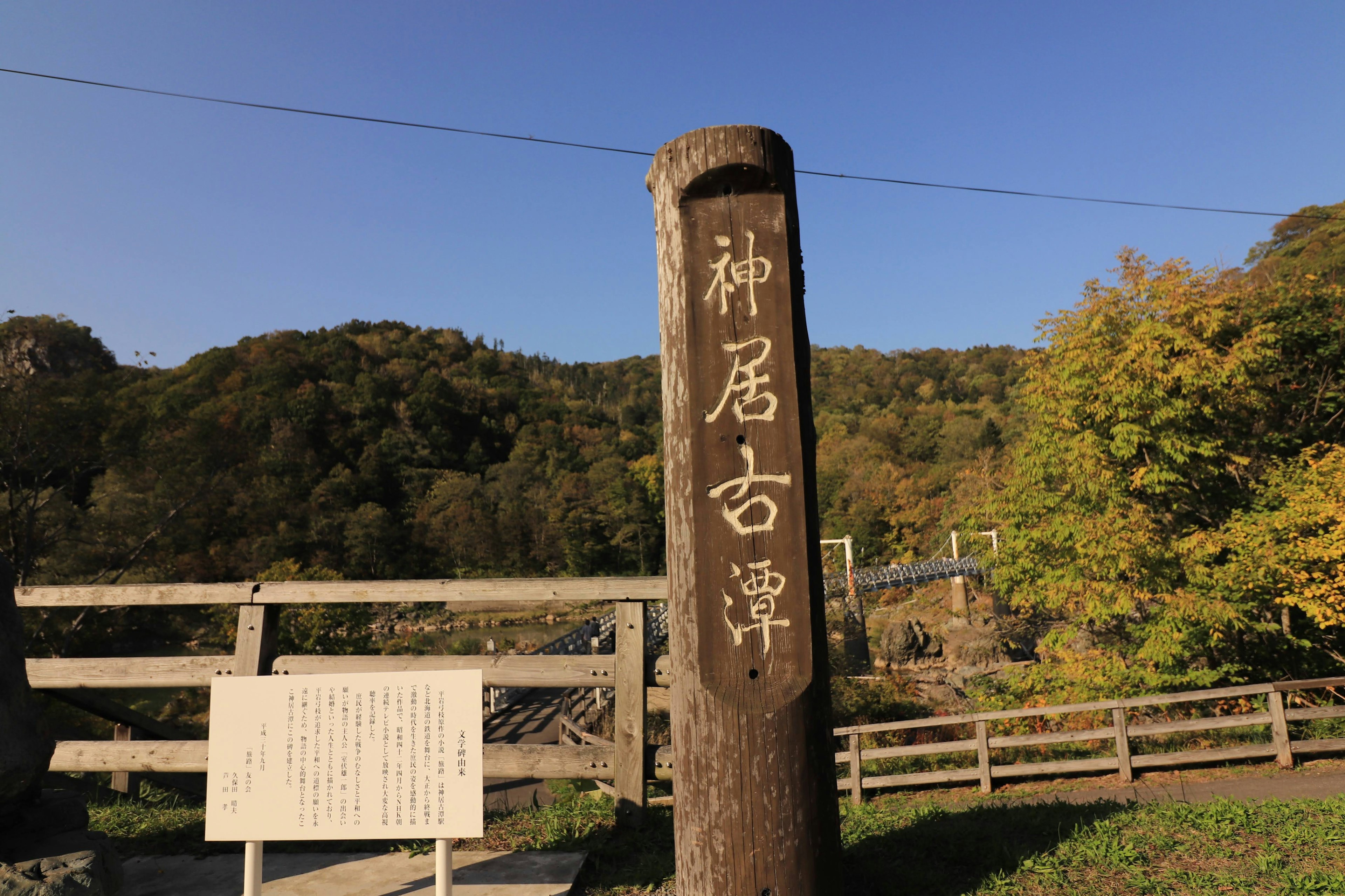 Señal de madera de Kamui Kotan con paisaje natural circundante