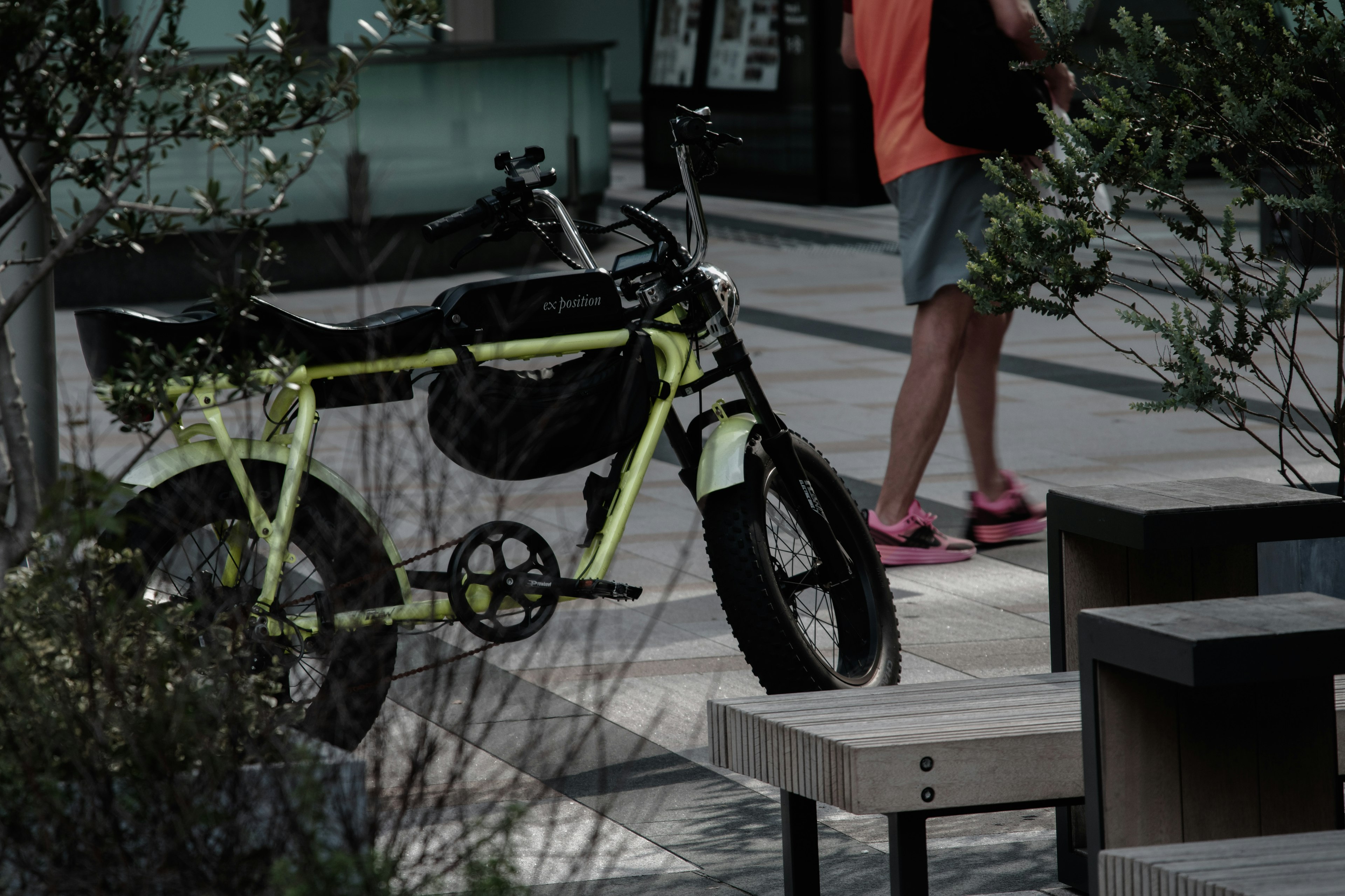 A person standing near a bicycle with green plants around