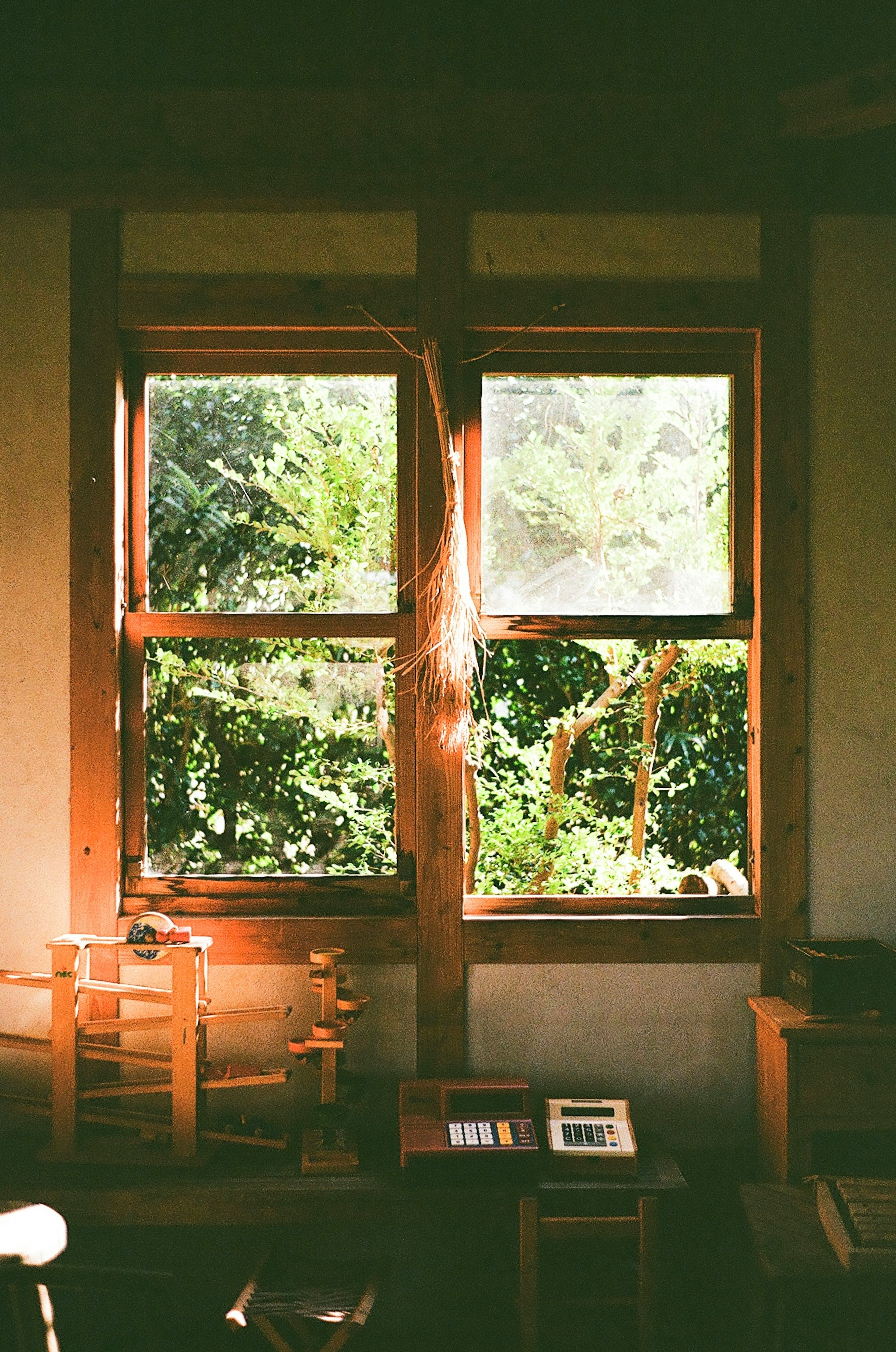 Wooden window revealing a lush green view and interior furniture