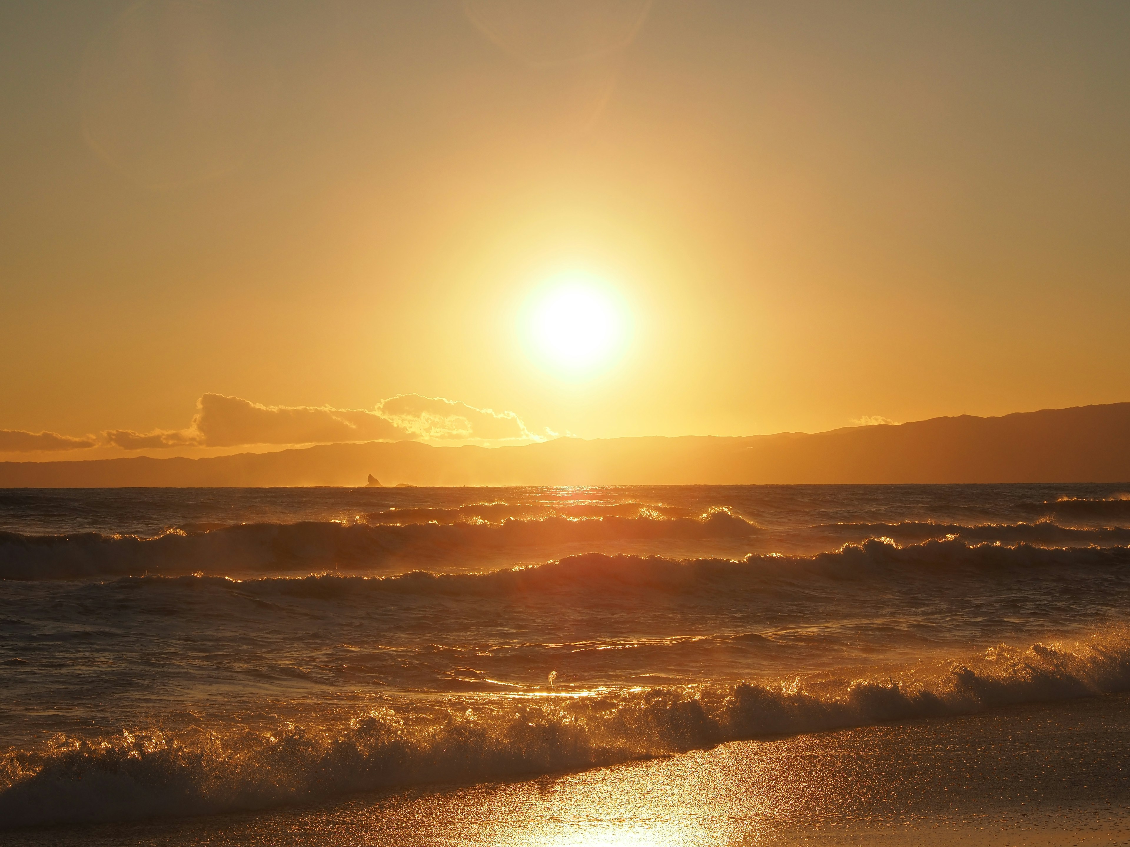 Beautiful sunset over the ocean with waves and light reflection