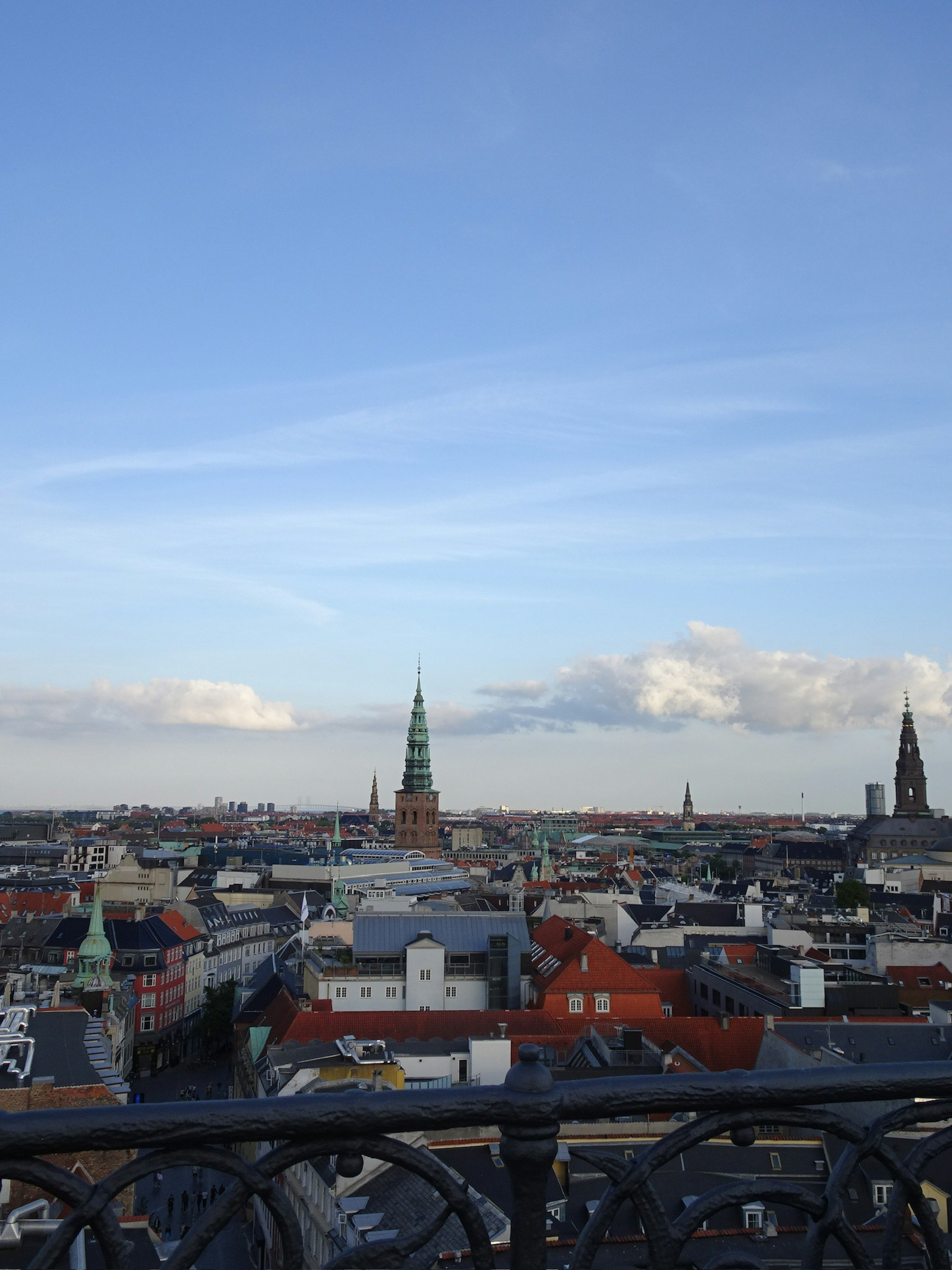 Panoramic view of Copenhagen skyline with blue sky and white clouds featuring green spires