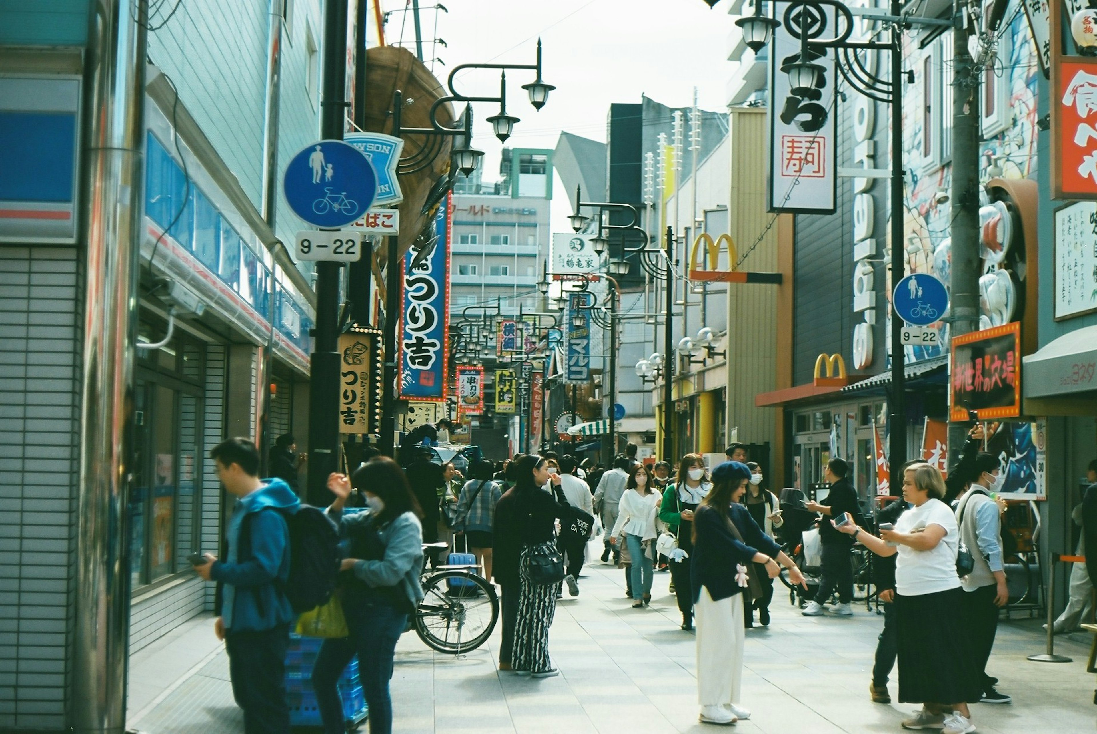 Calle comercial concurrida con gente y señales