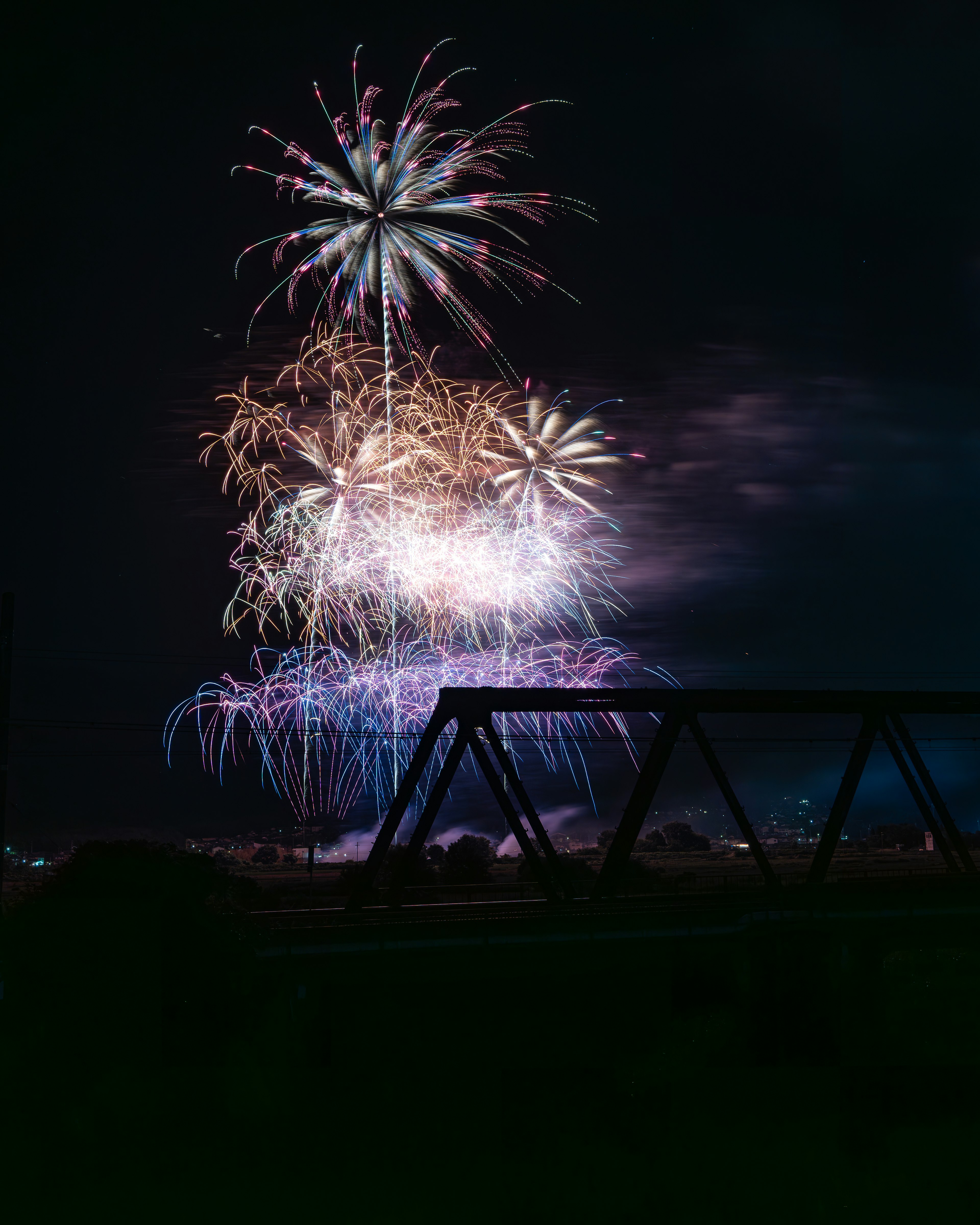 Espectáculo de fuegos artificiales coloridos en el cielo nocturno con una estructura en primer plano