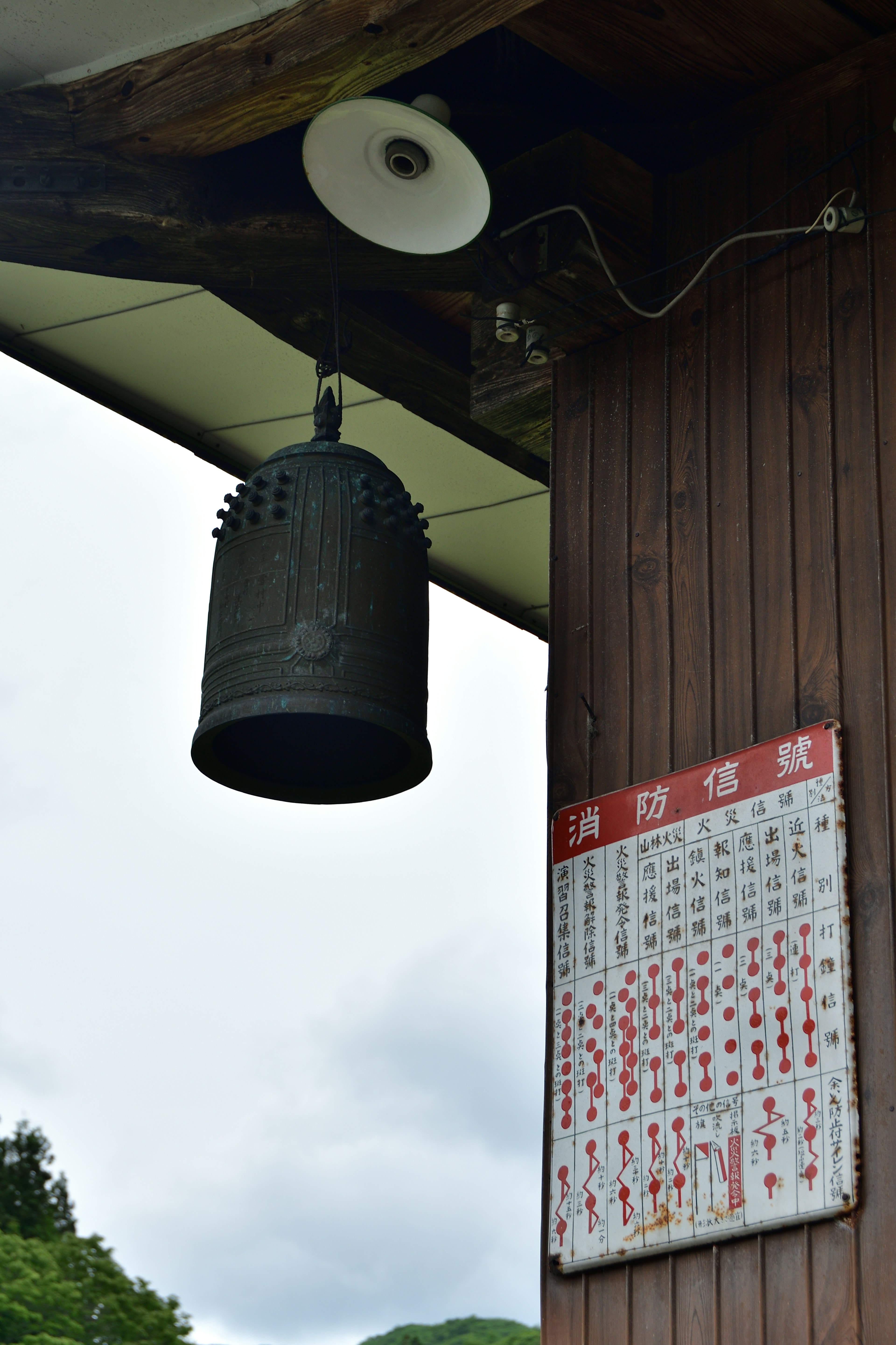 古い鐘とカレンダーが掛かっている木製の柱の風景