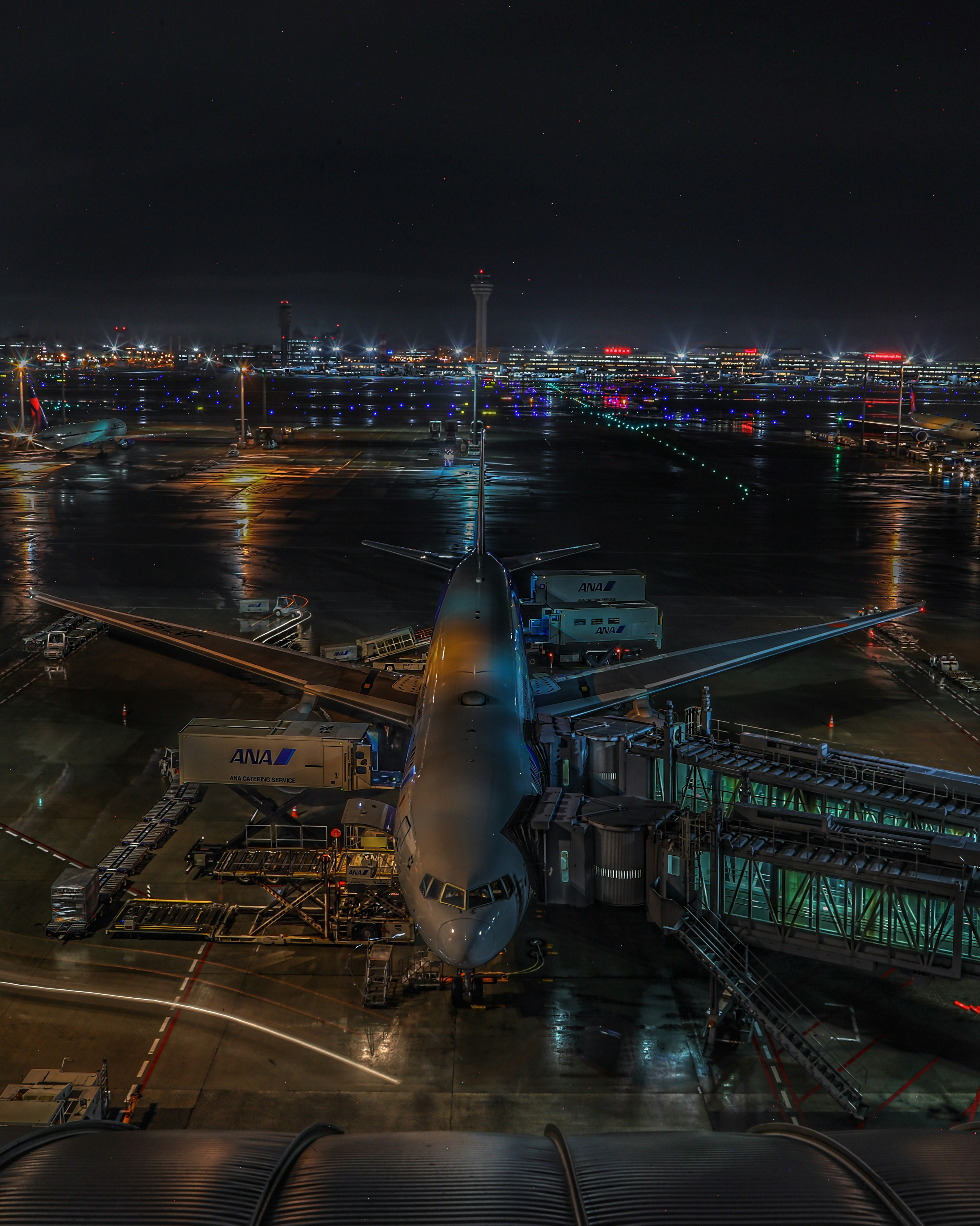 夜景の空港に停まる航空機と輝く都市の景色