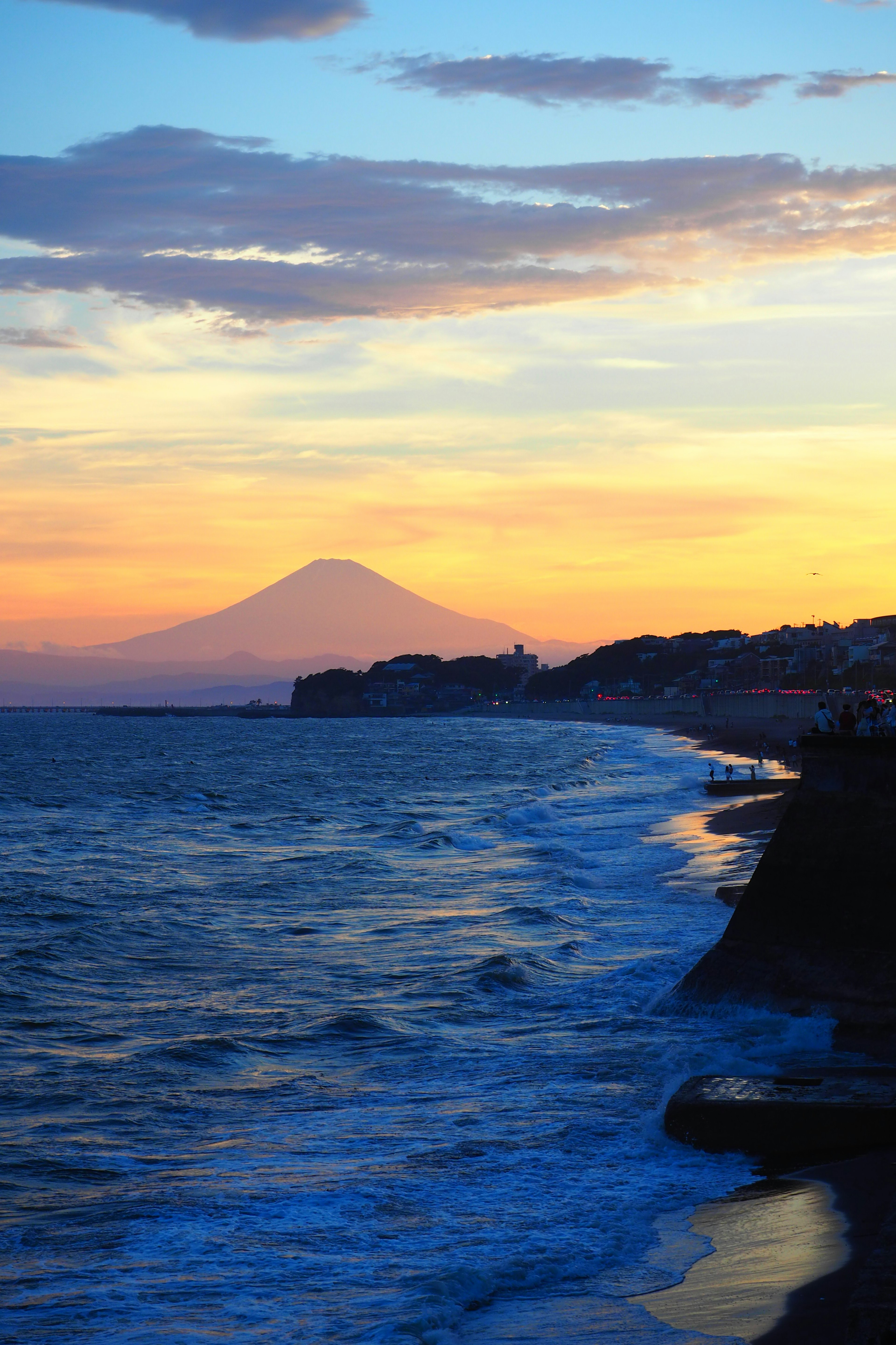 Pemandangan indah dengan lautan biru dan gunung saat matahari terbenam