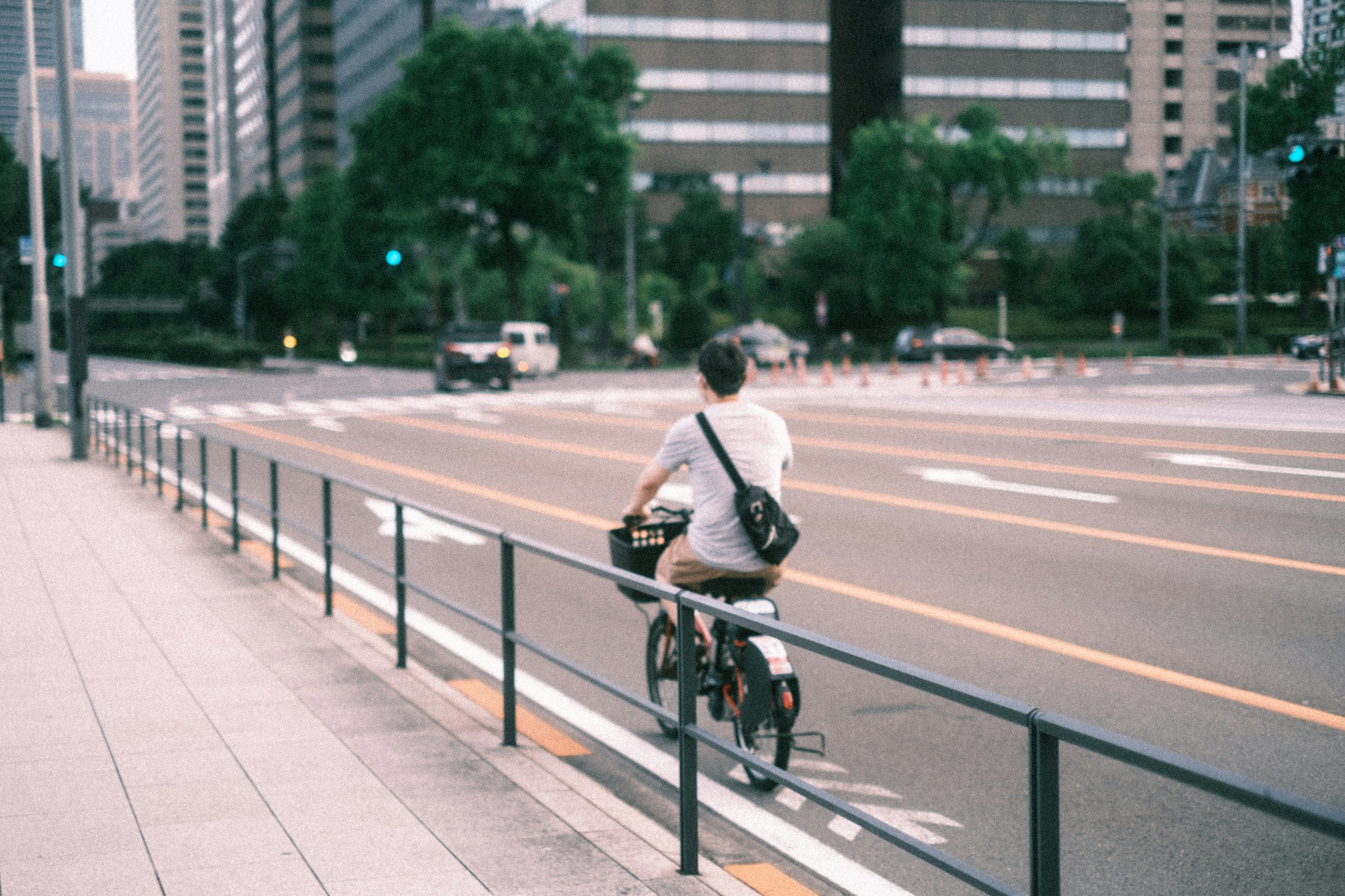 Person riding a bicycle on an urban street with tall buildings in the background