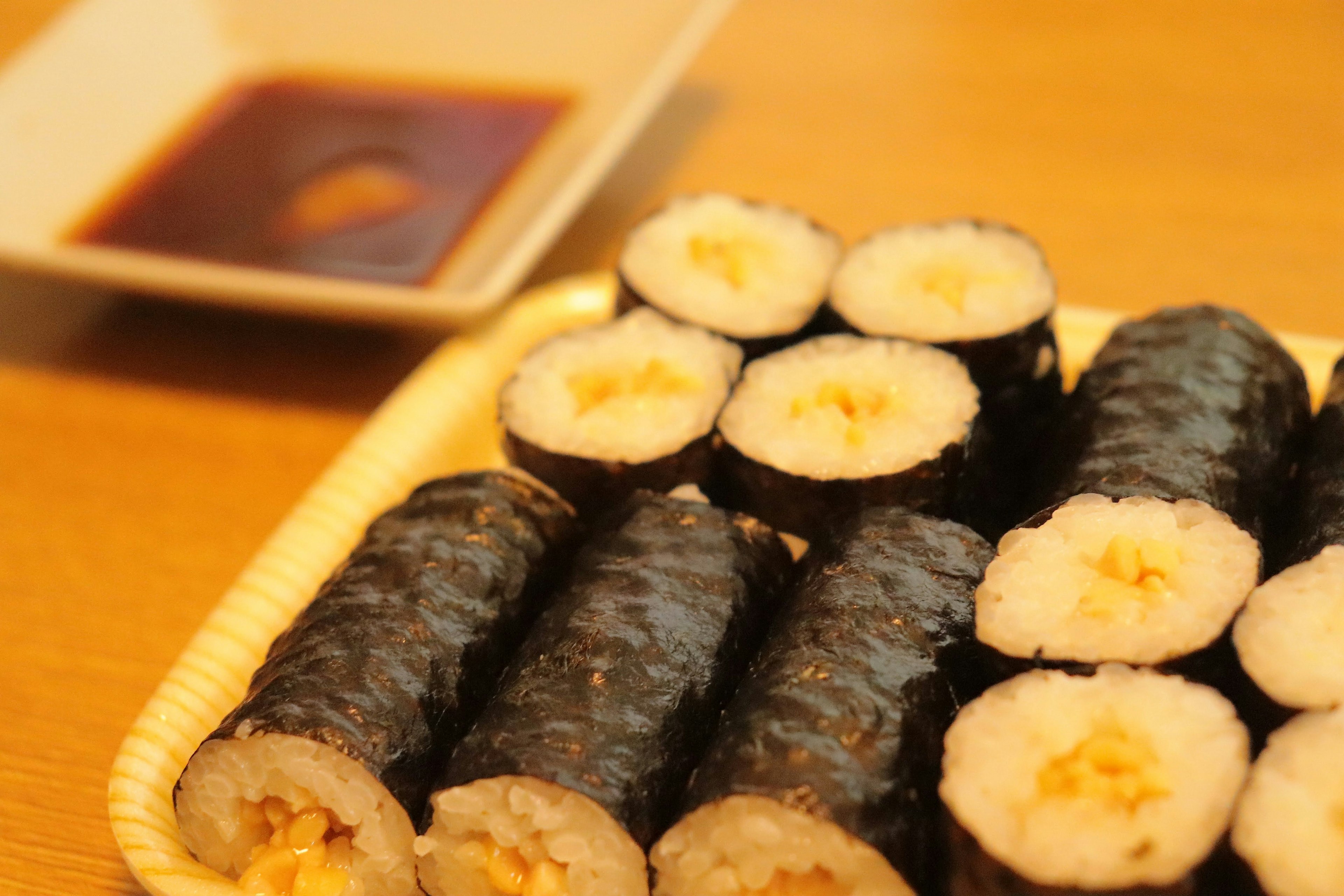 Deliciosos rollos de sushi dispuestos en un plato con un pequeño recipiente de salsa de soja