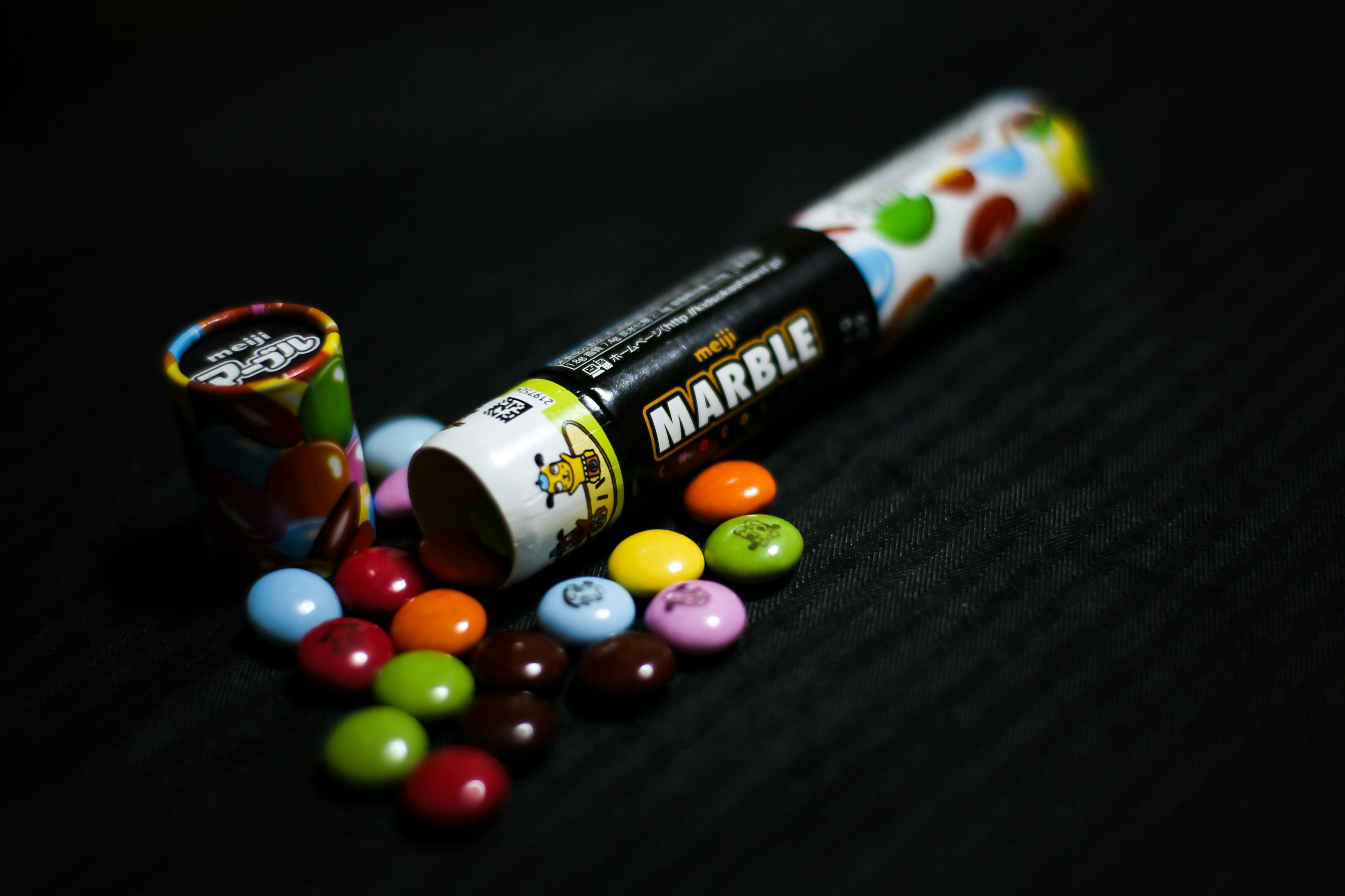 Colorful candies and a marble tube on a black background