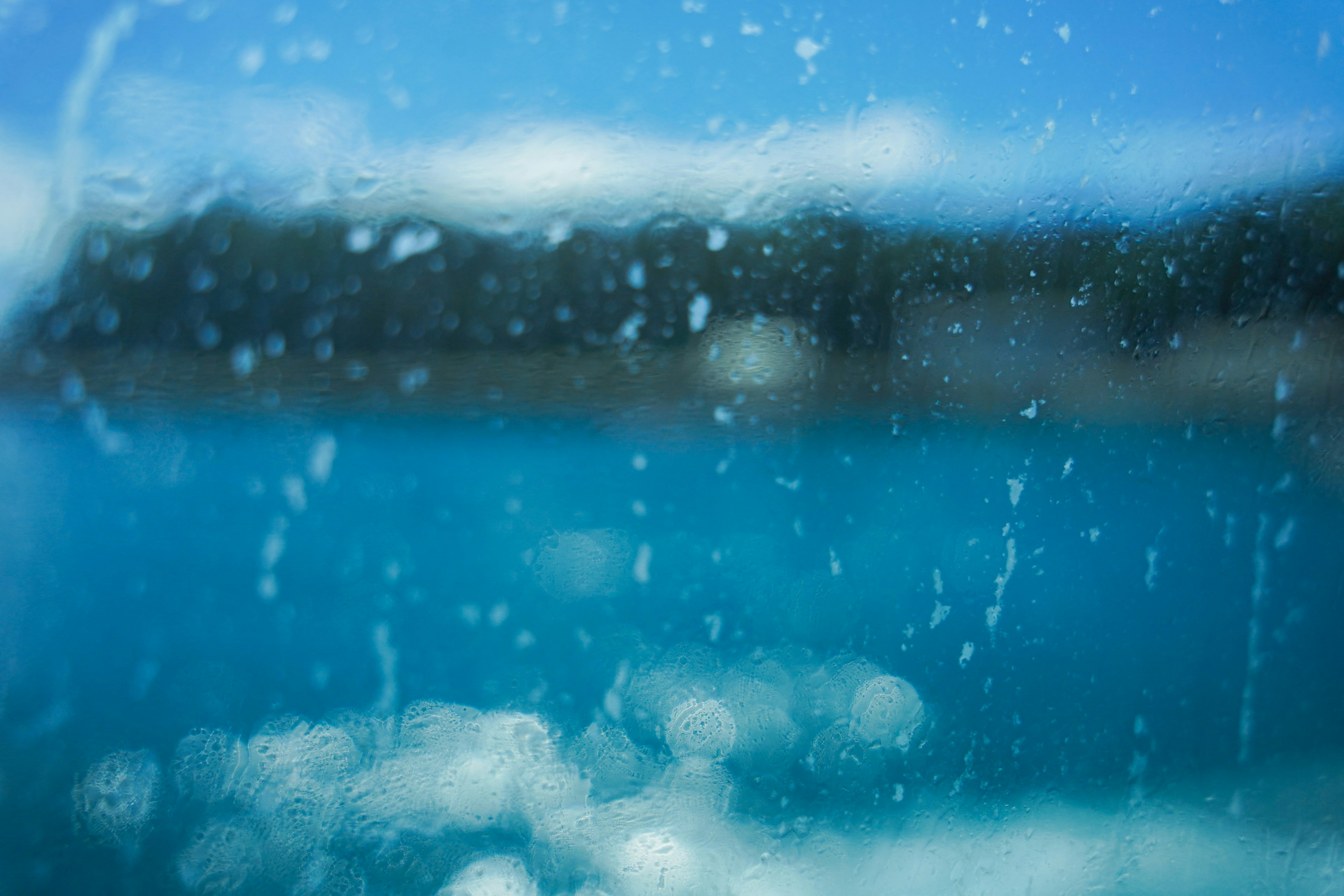 青い海と水滴のある窓越しの風景