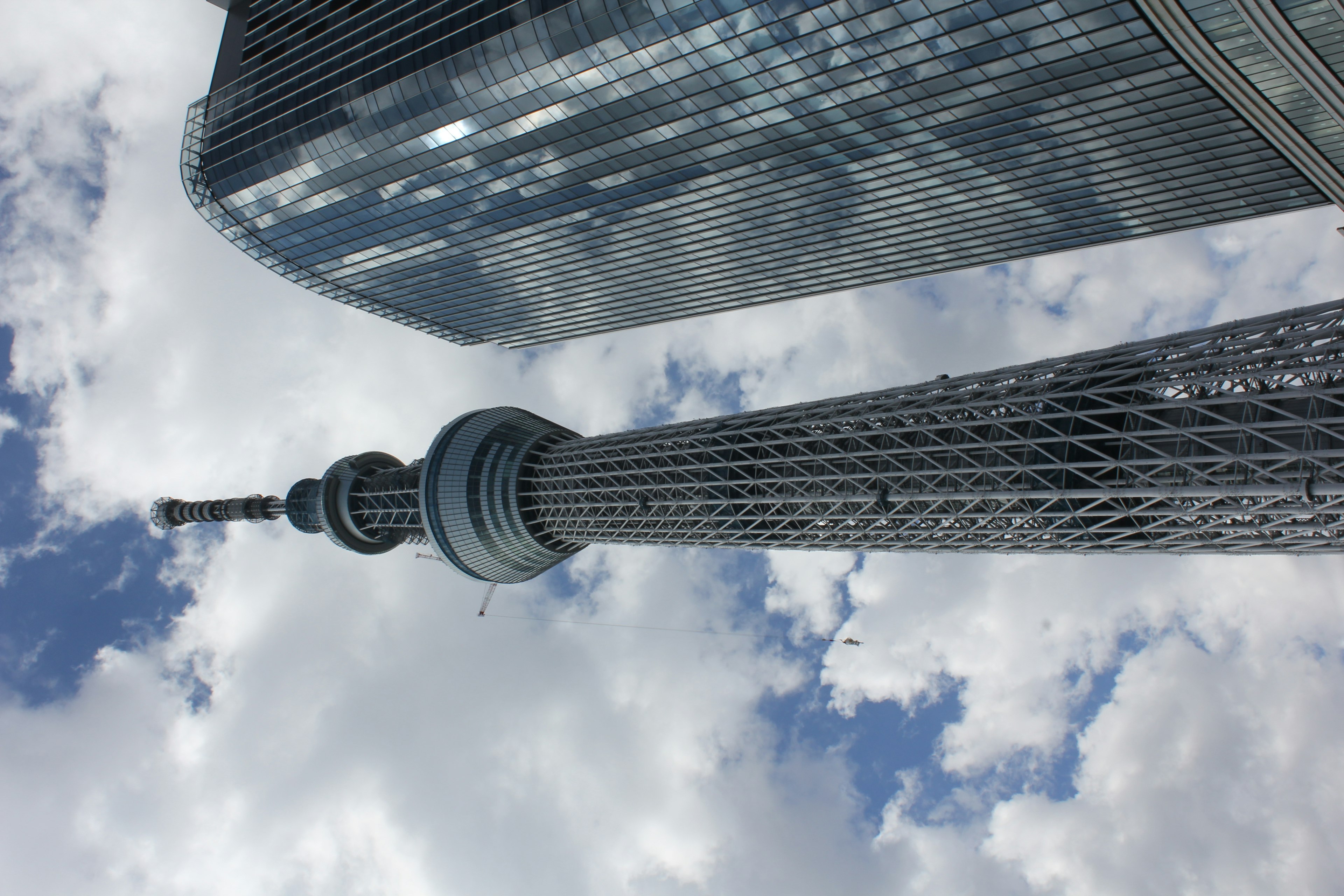 Tokyo Skytree với tòa nhà kính gần đó và bầu trời nhiều mây