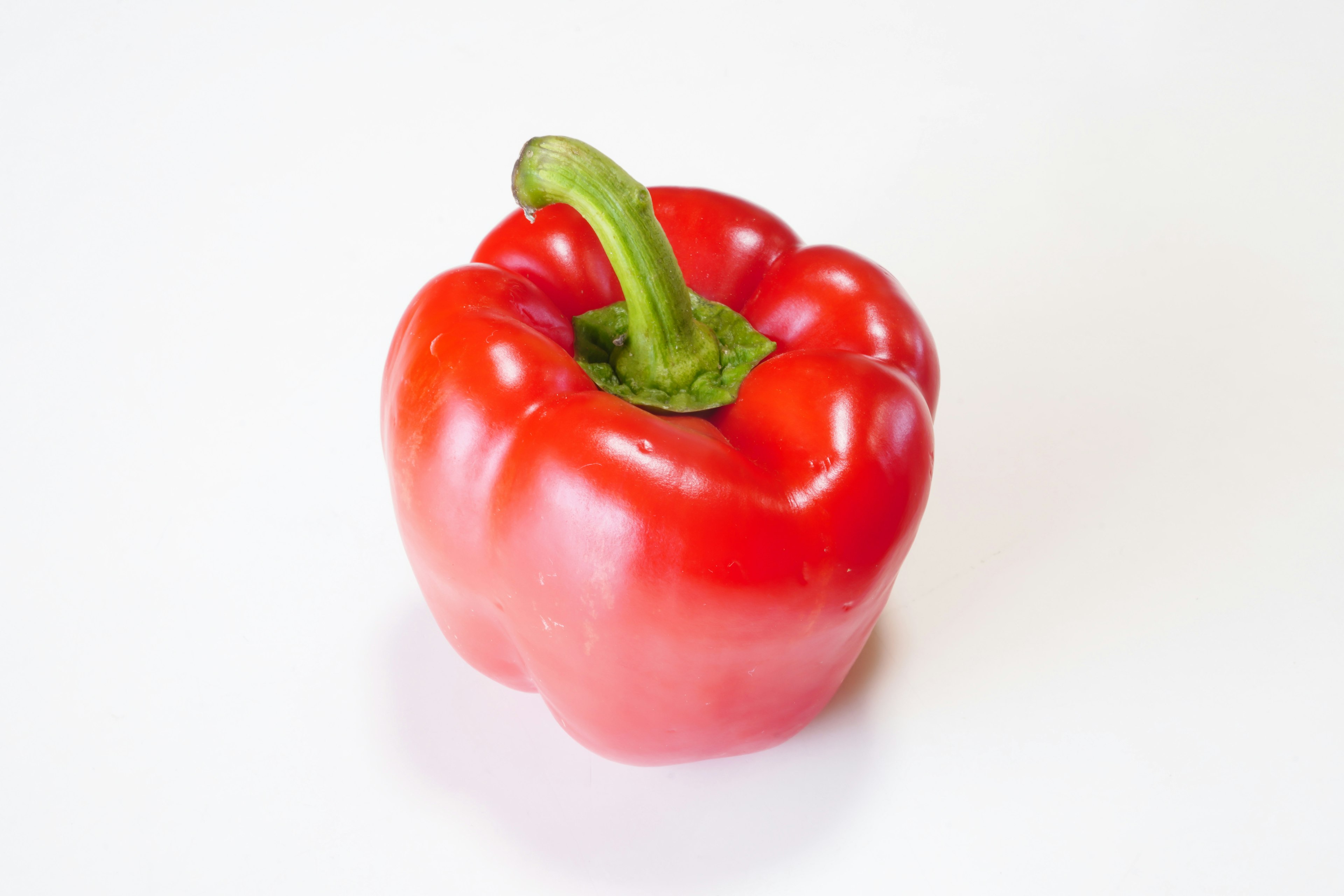 A vibrant red bell pepper placed on a white background