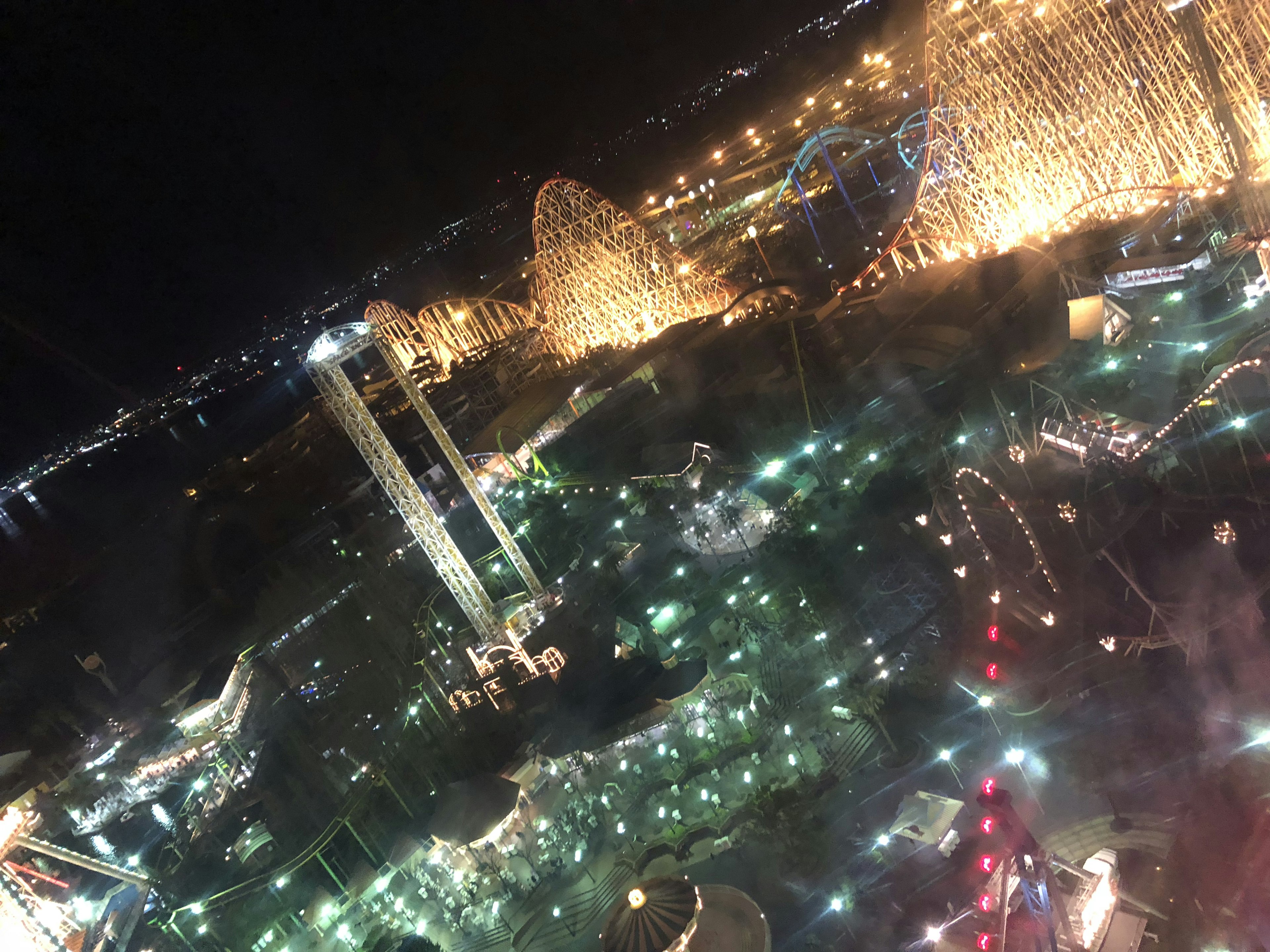 Night view of an amusement park with sparkling lights and attractions visible