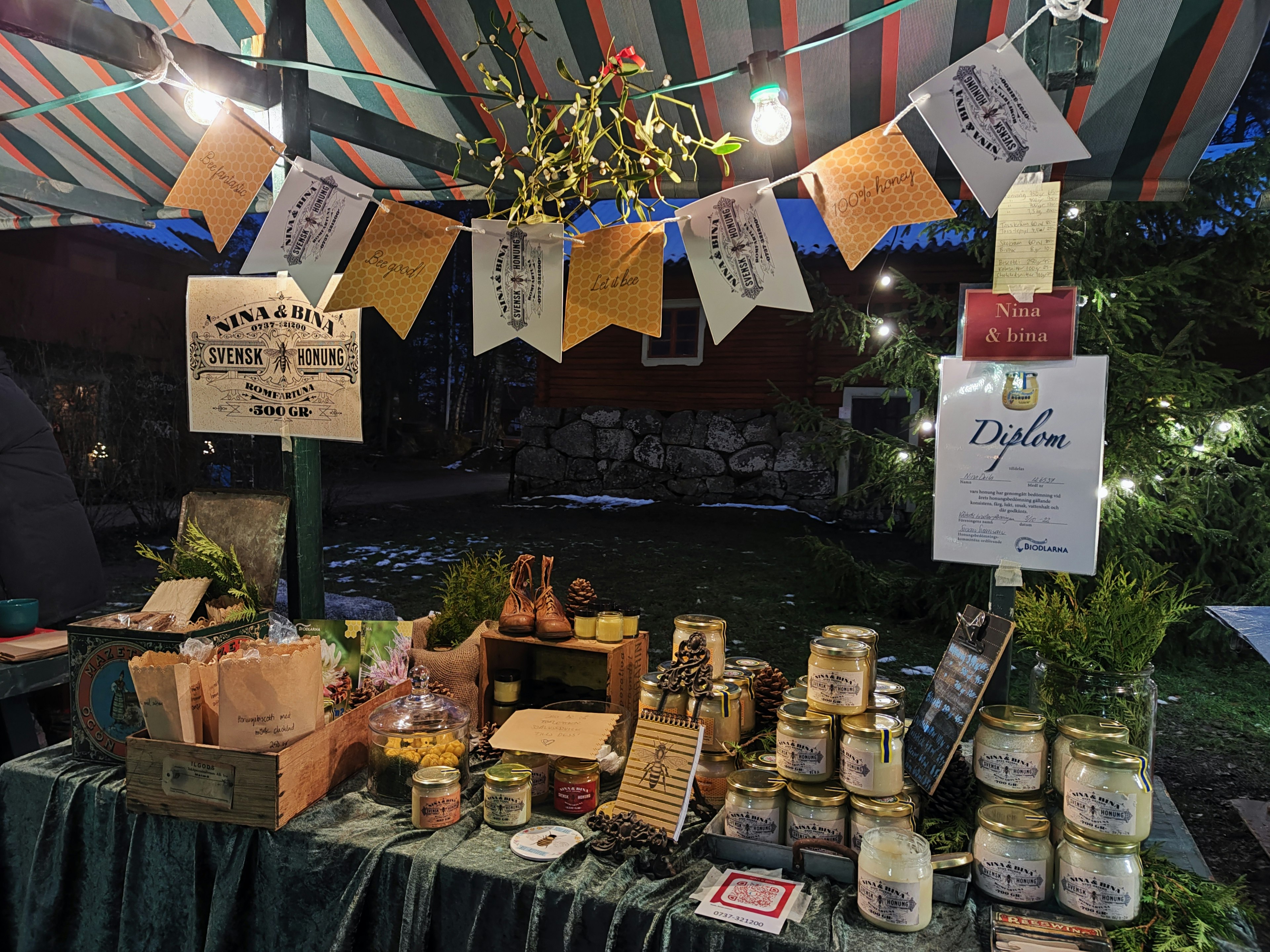 Stand auf einem Freiluftmarkt mit handgemachten Marmeladen und eingelegtem Gemüse sowie dekorativen Bannern