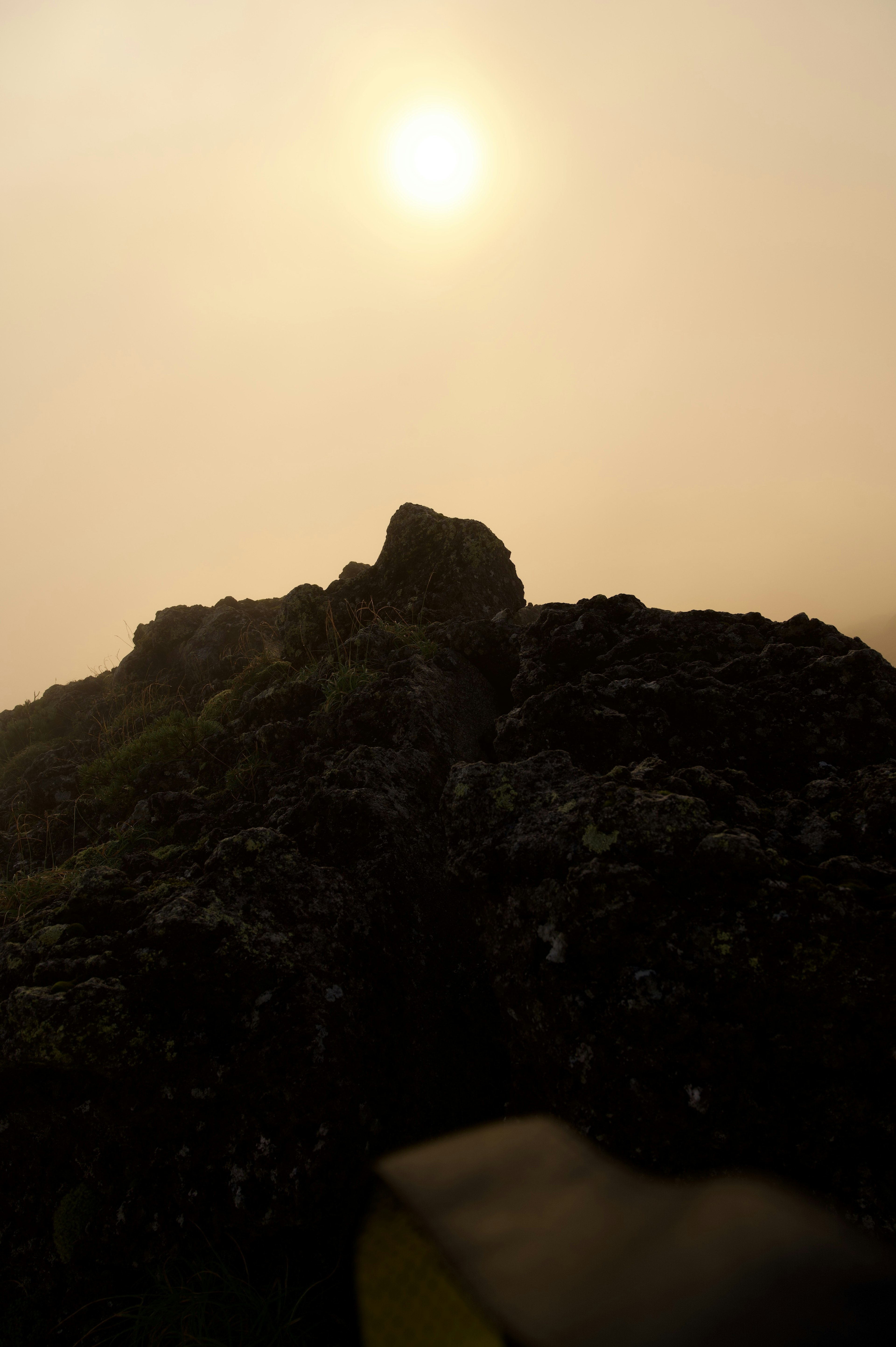 Rocce di montagna nebbiose con luce solare