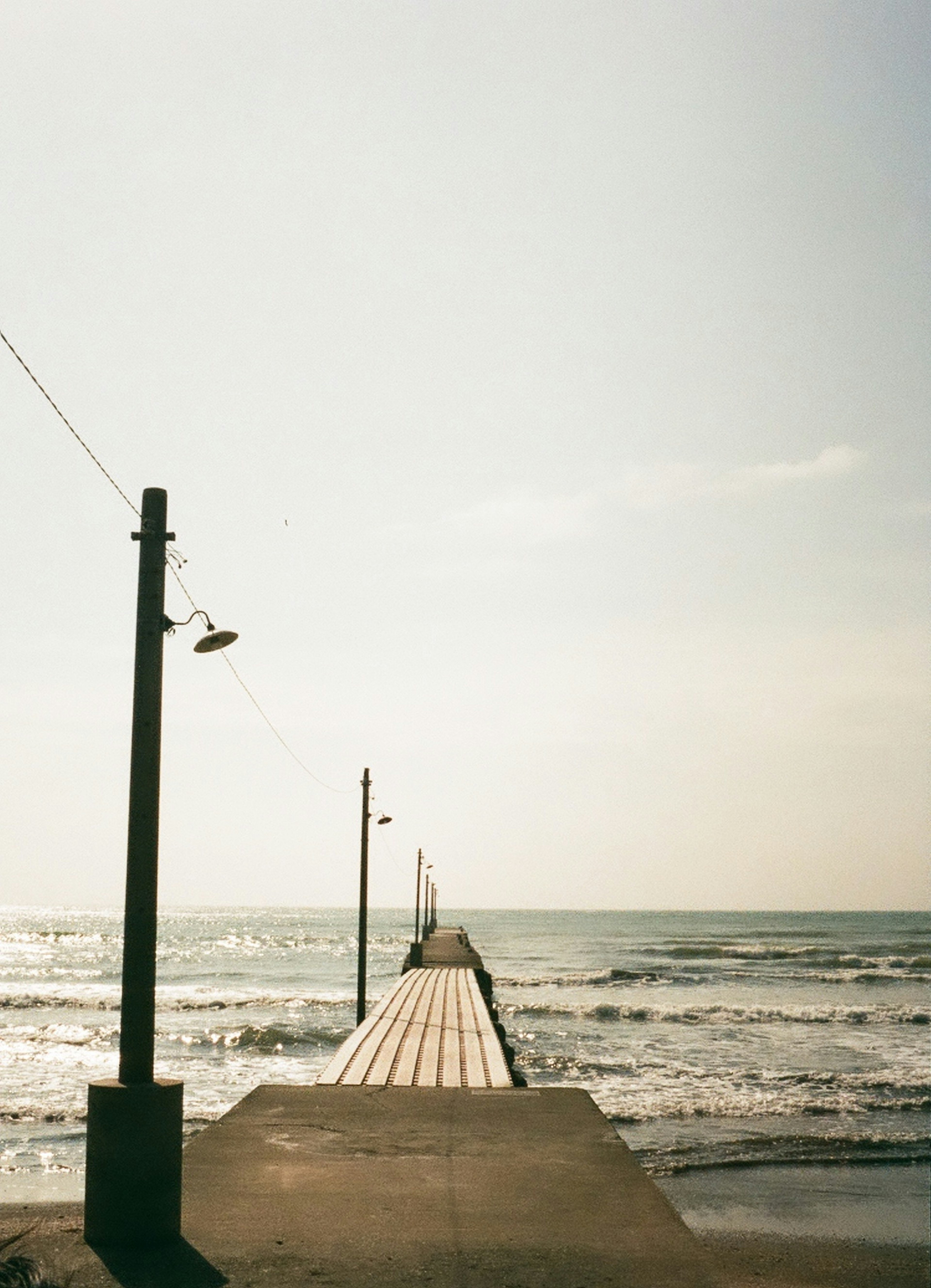 Long pier extending into the sea with gentle waves