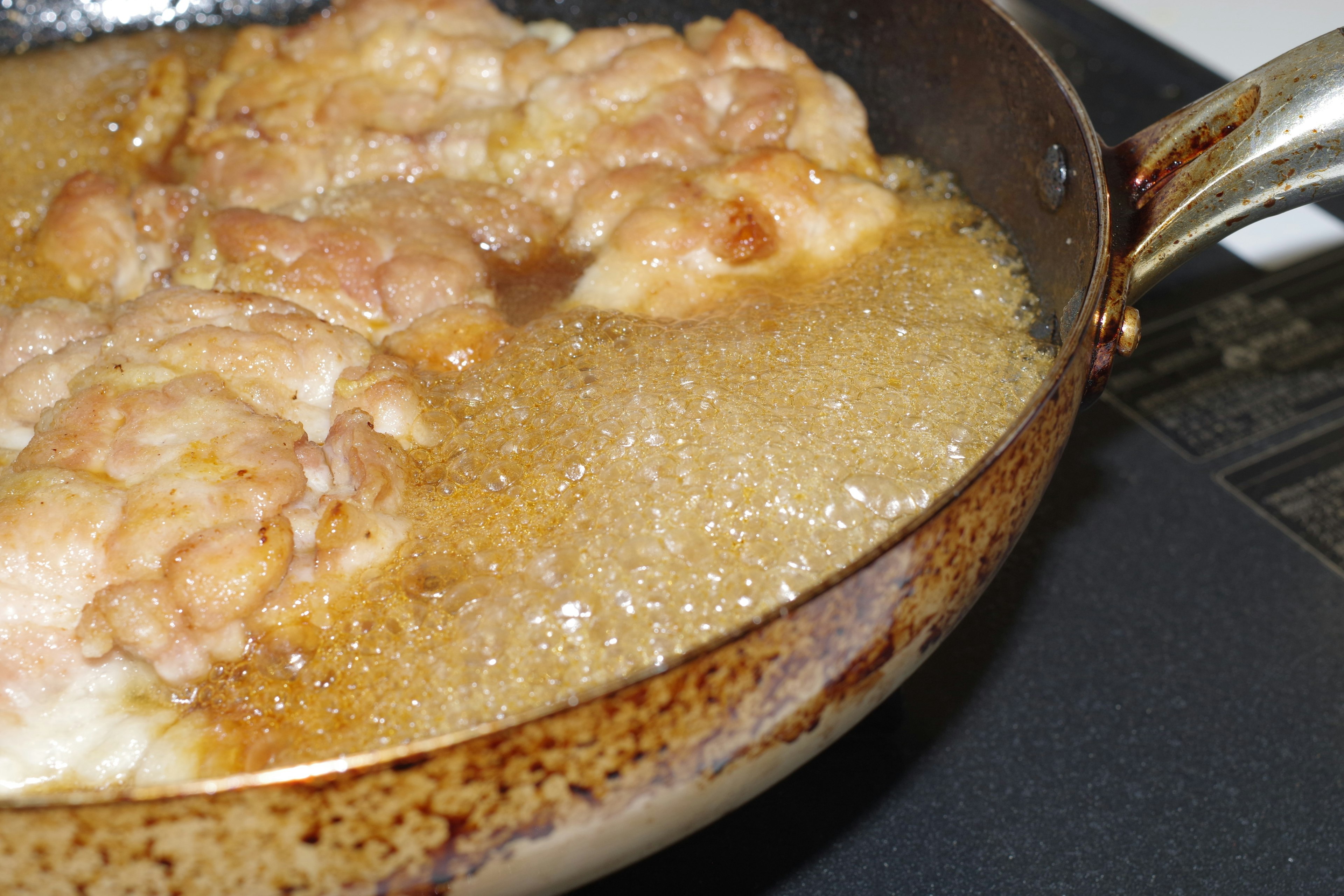 Chunks of chicken frying in a pan with bubbling oil