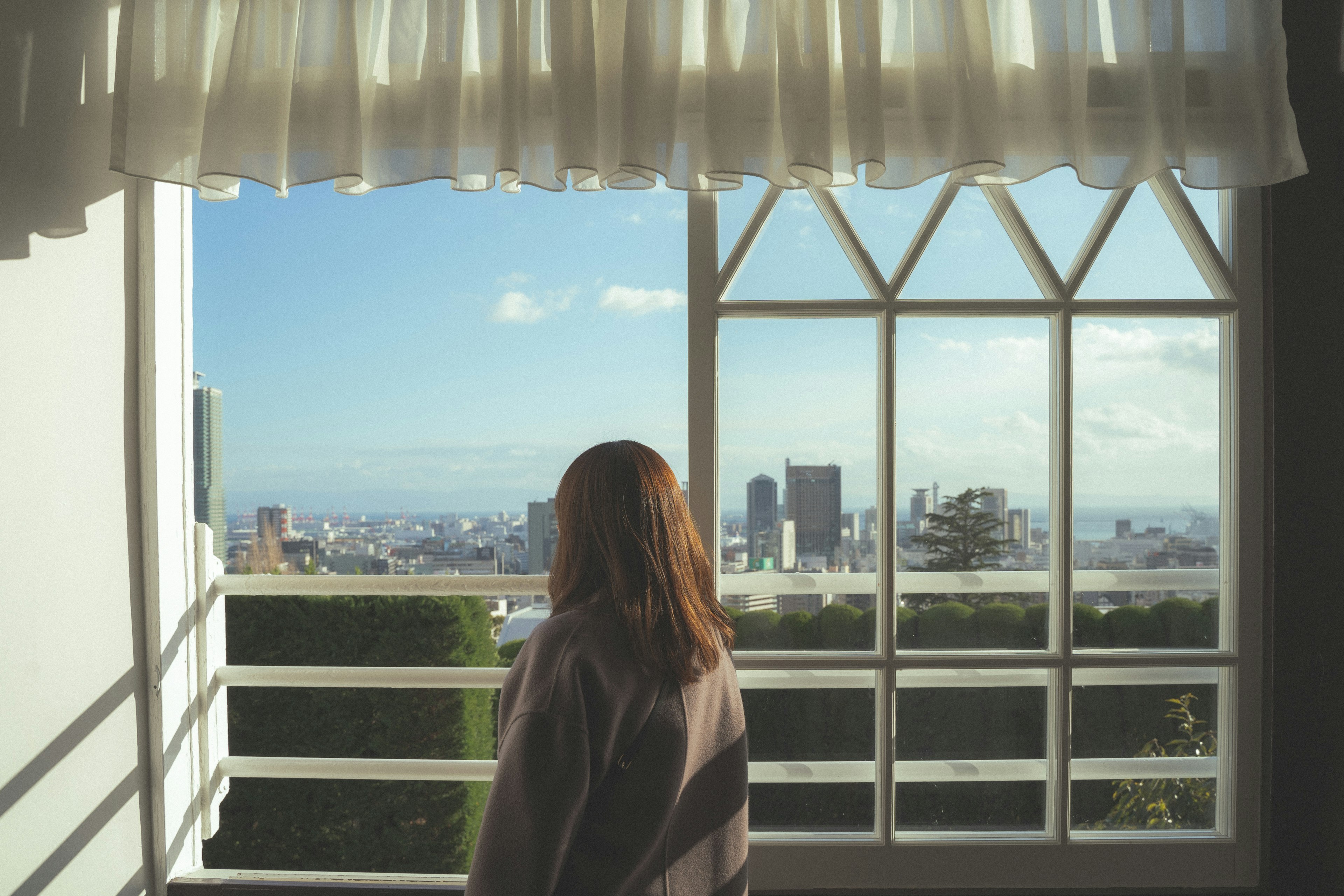 Frau, die aus dem Fenster auf eine Stadtlandschaft schaut