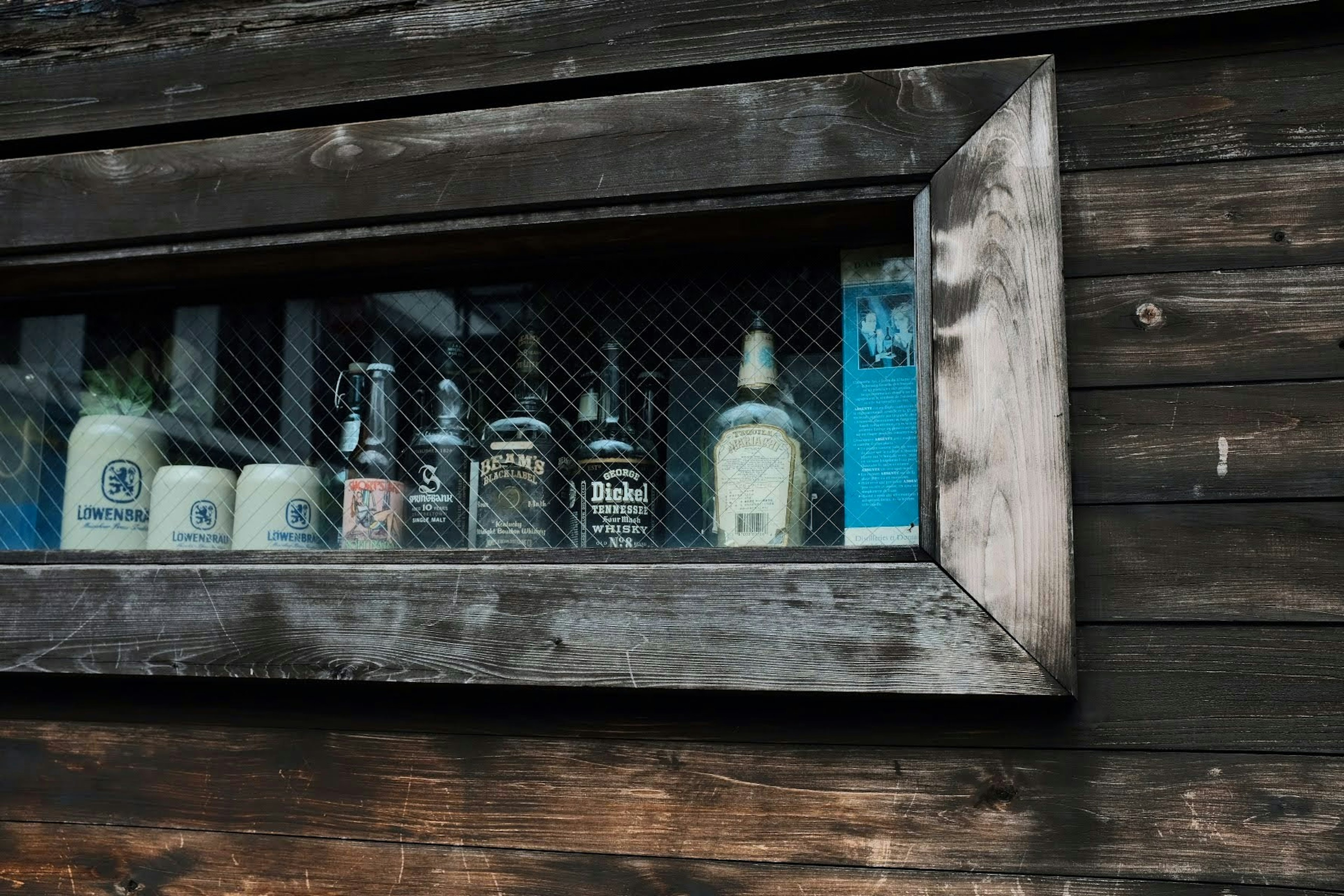 Collection of bottles displayed in a wooden window frame