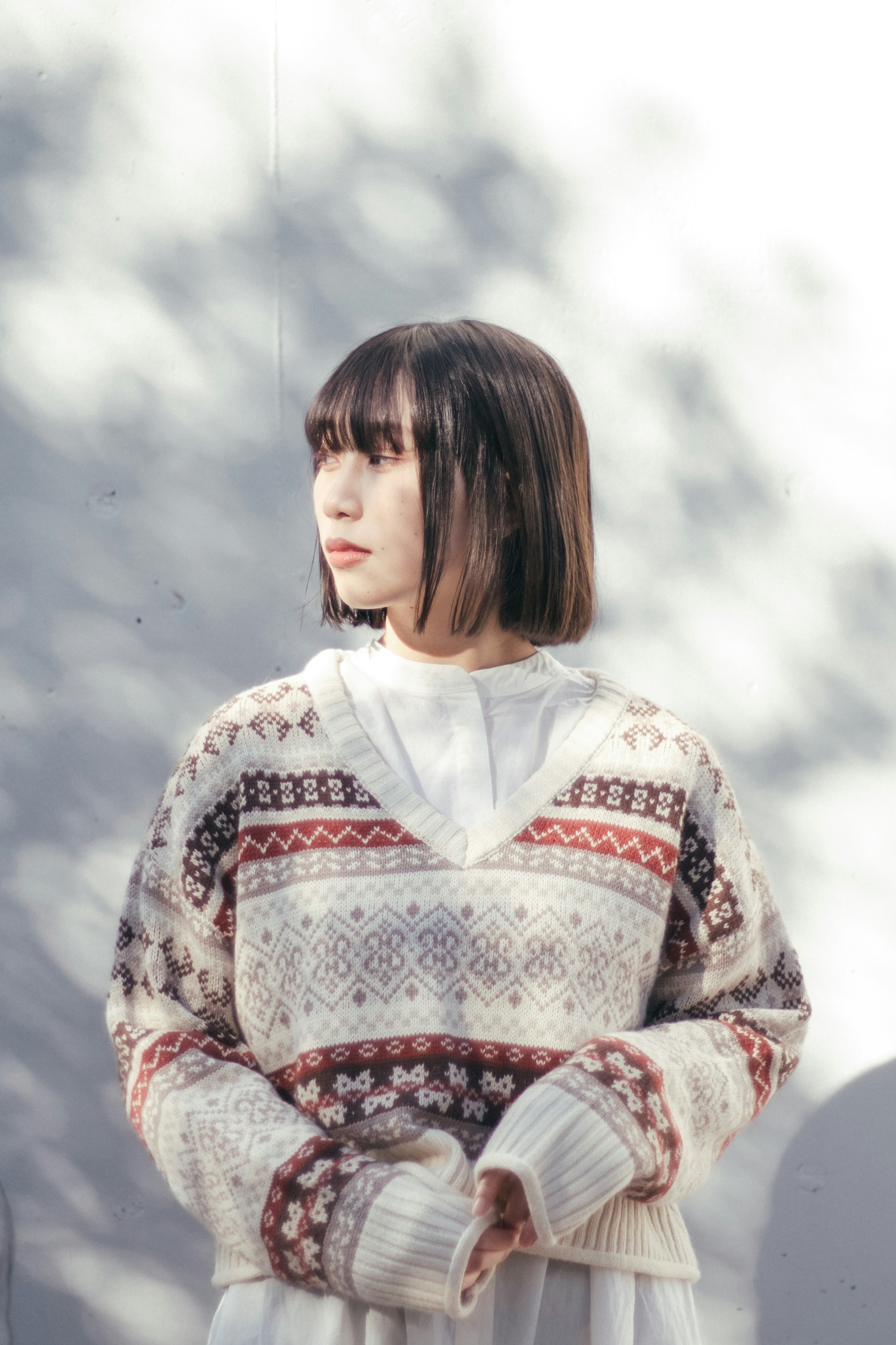 A woman standing in the shade wearing a patterned sweater