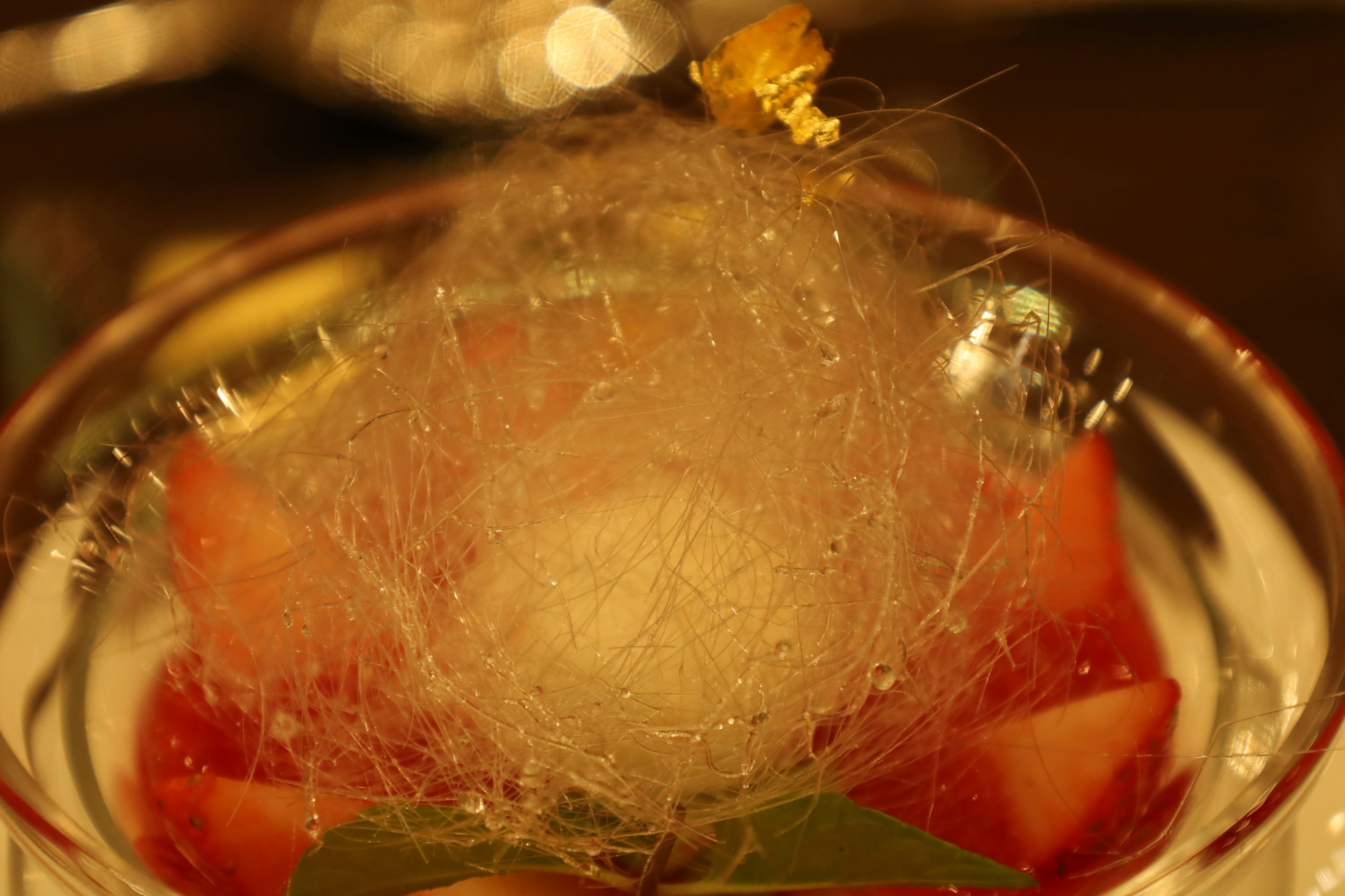 Un dessert avec du sucre filé sur des tranches de fruits et une boule de glace