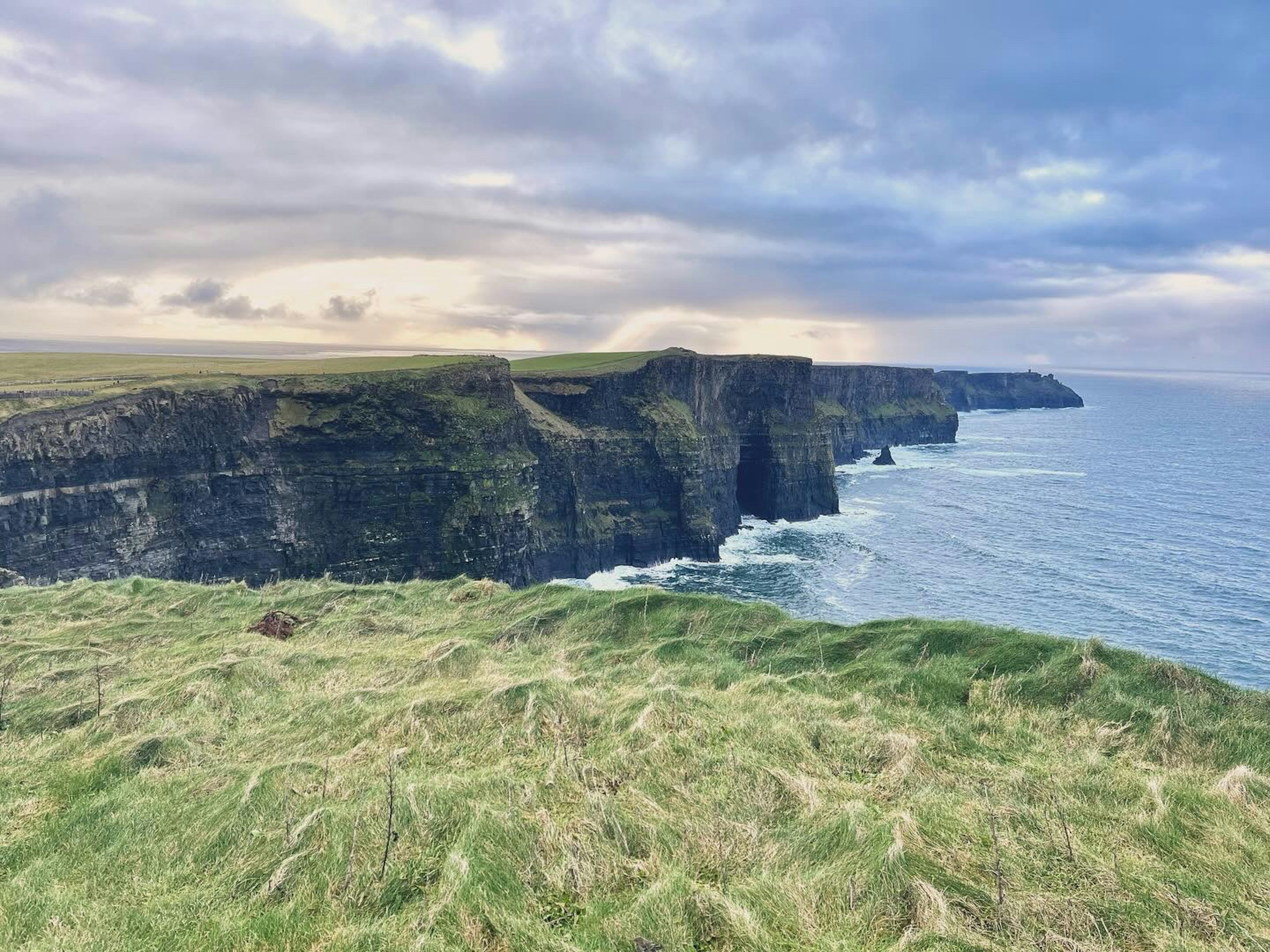 Vista drammatica delle Cliffs of Moher in Irlanda con erba verde e oceano