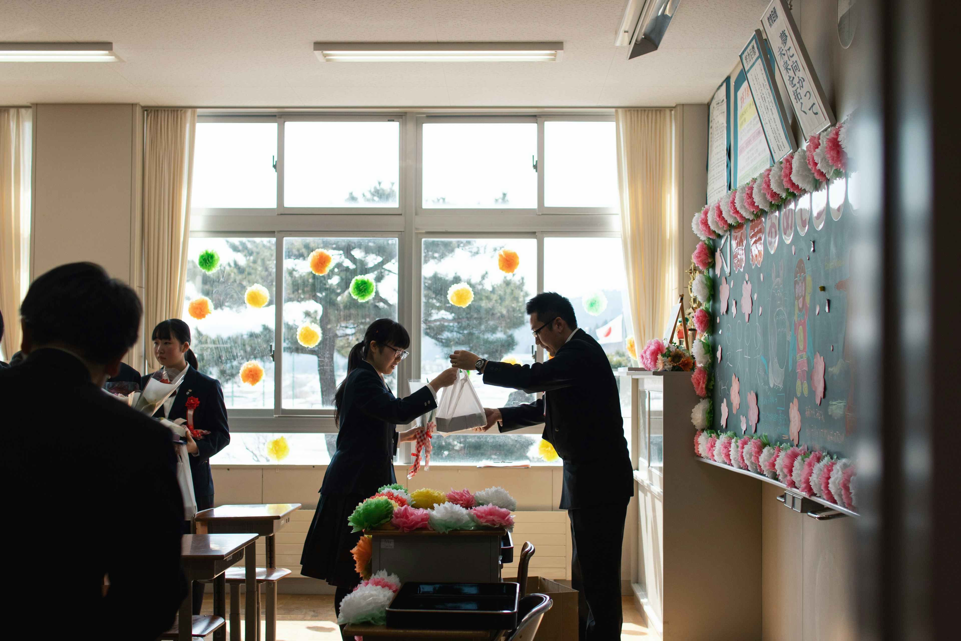 Students exchanging bouquets in a classroom during a graduation ceremony