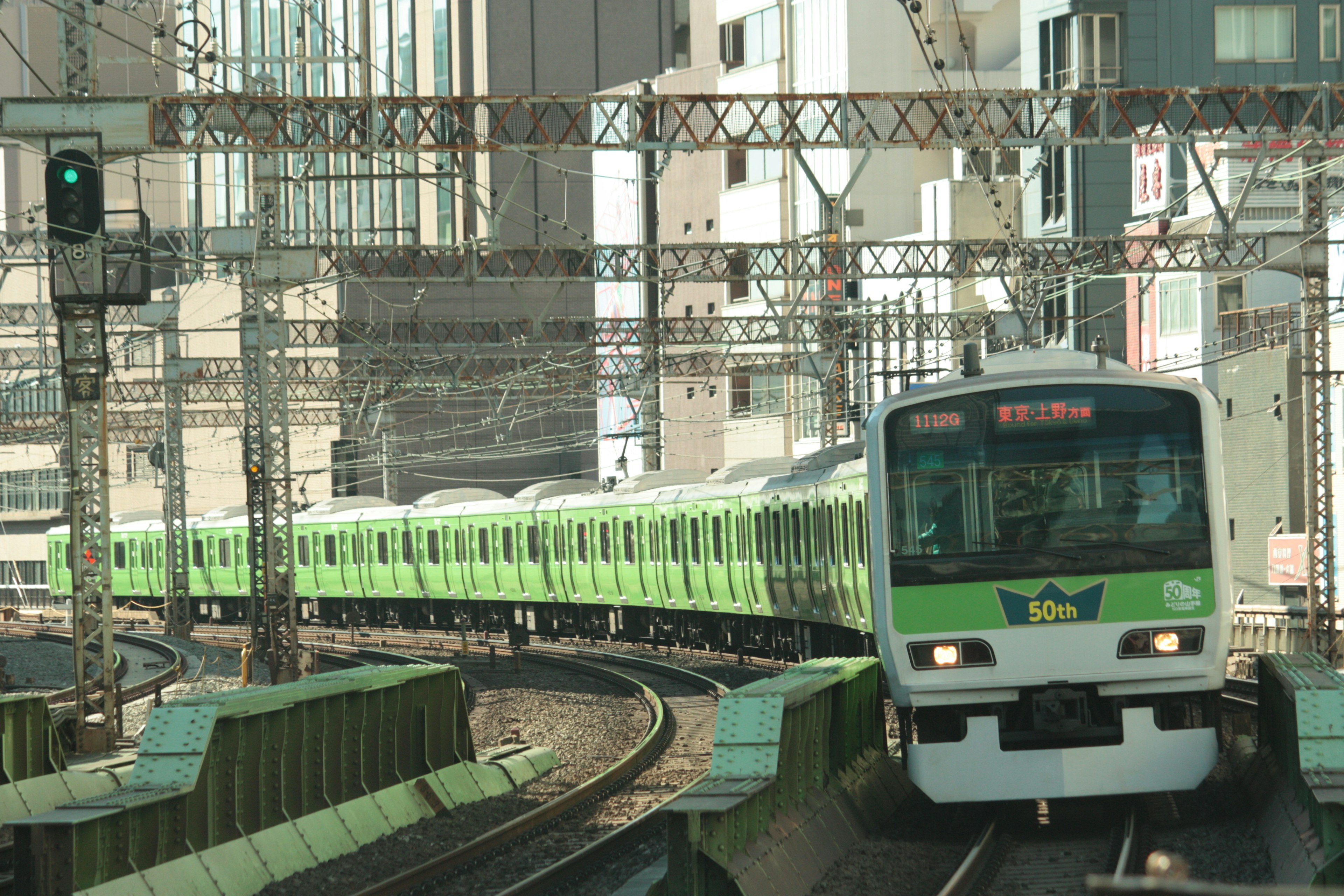 Treno verde che naviga in una curva in un paesaggio urbano