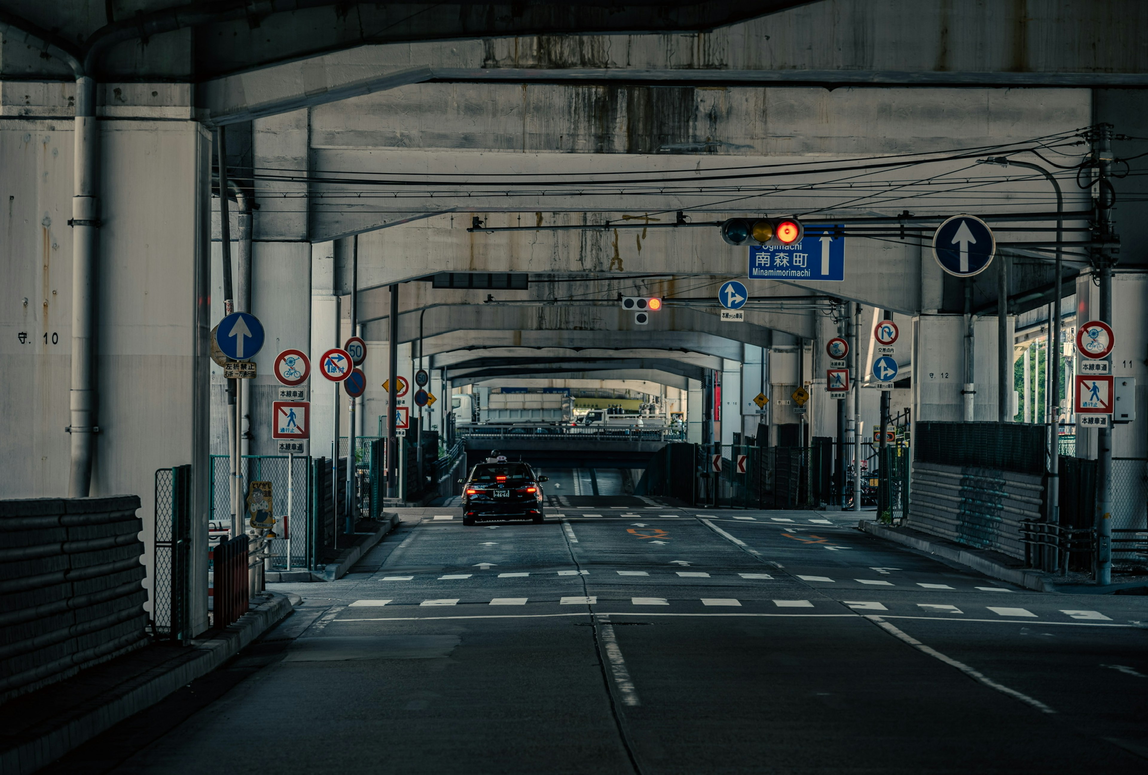 Road under an elevated structure with traffic lights and signs