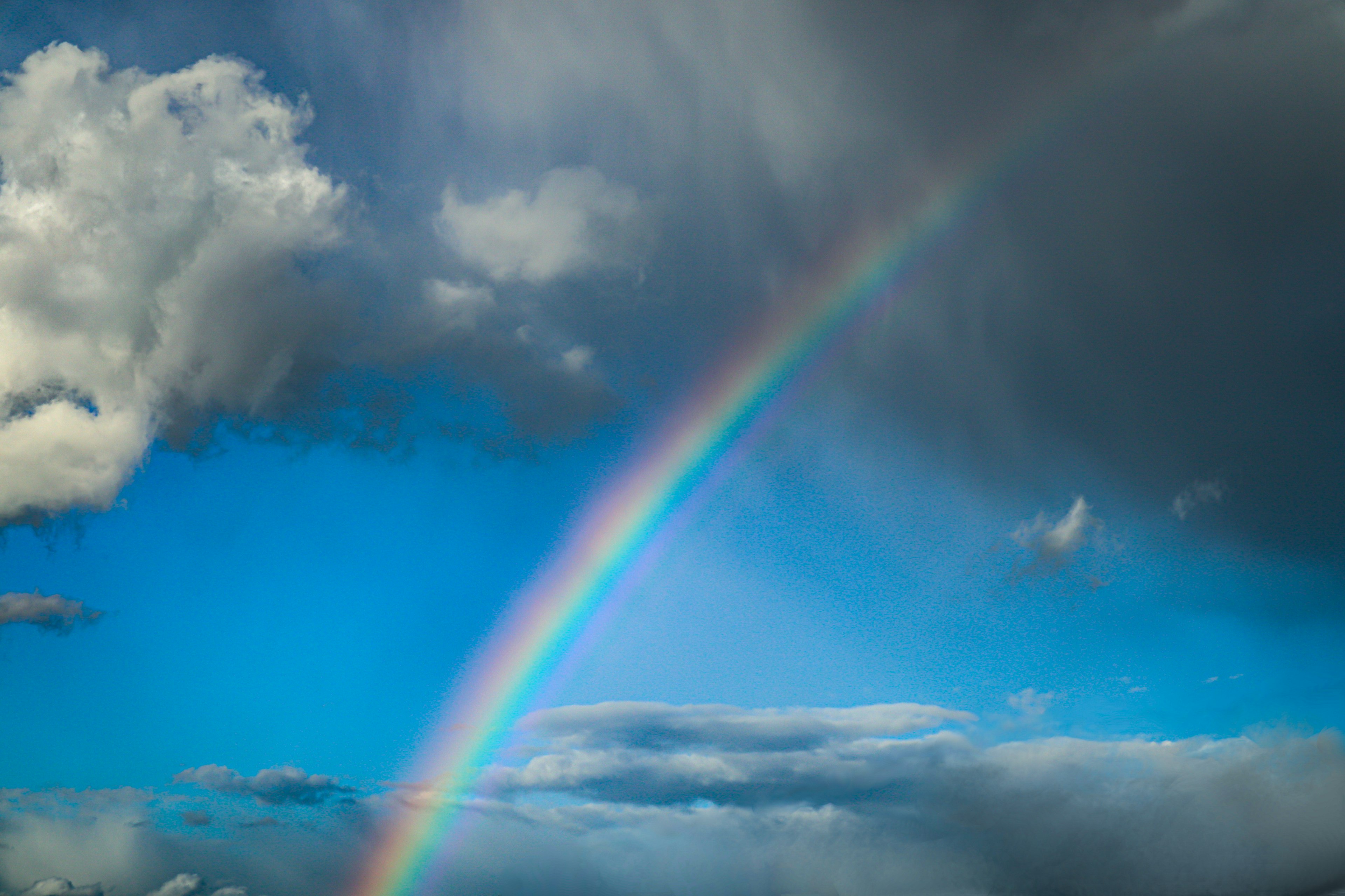 Ein Regenbogen, der über einen blauen Himmel mit Wolken spannt