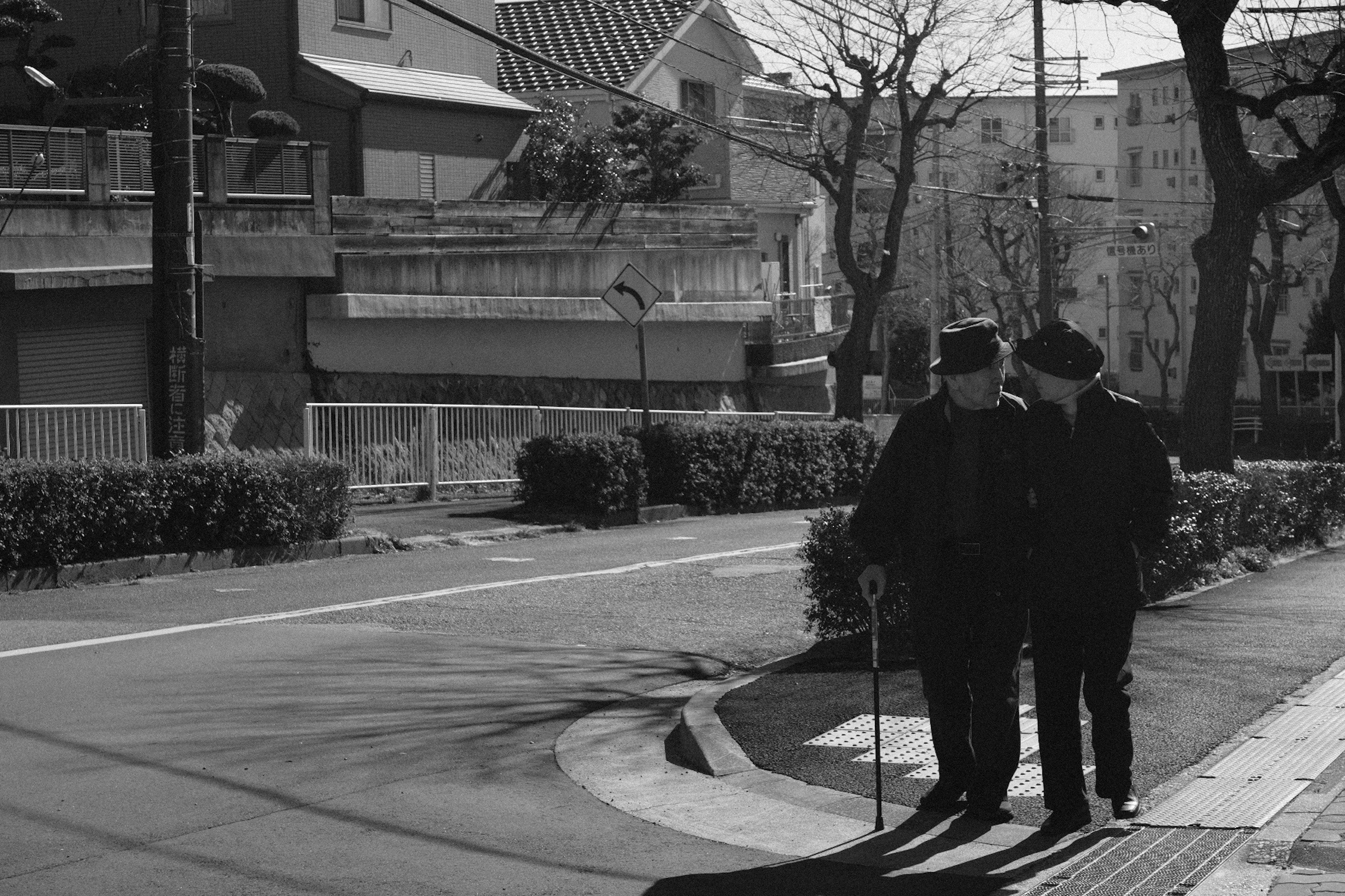 Two men conversing on a street corner in black and white