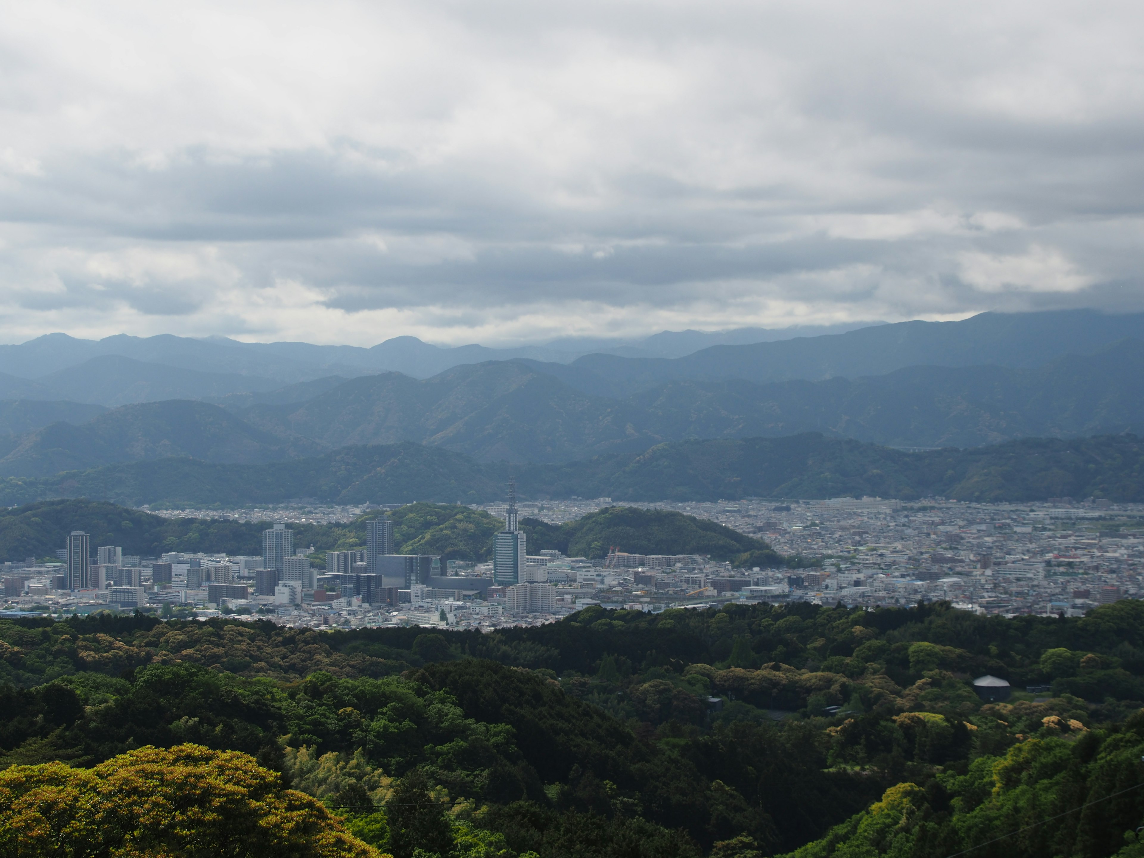 Scenic view of lush mountains and city skyline