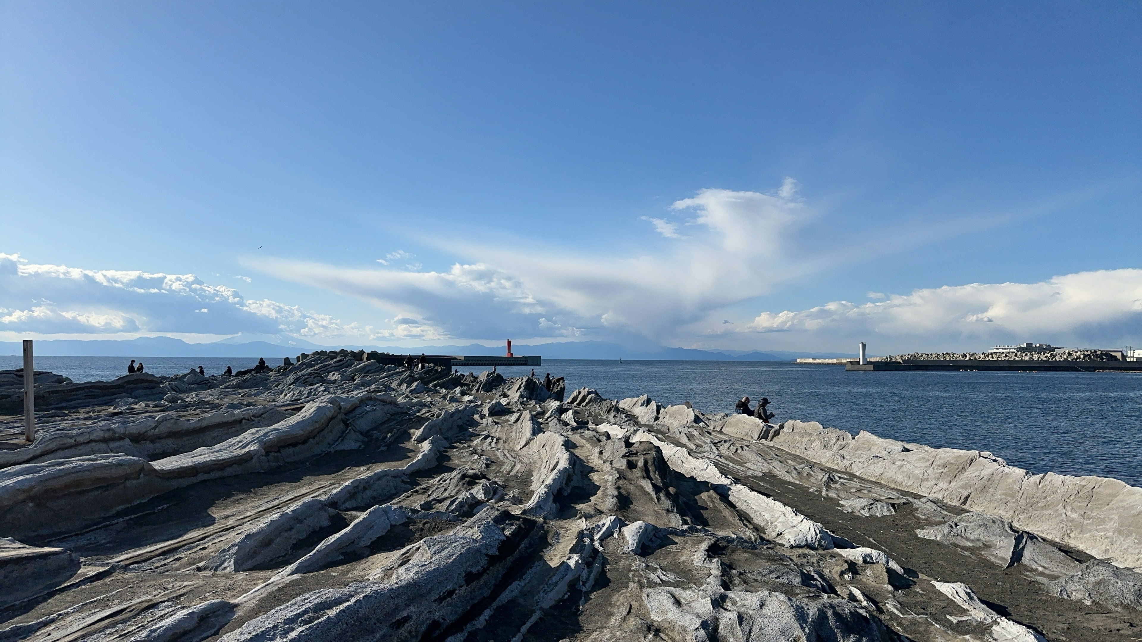 青空と雲が広がる海岸の岩場の風景