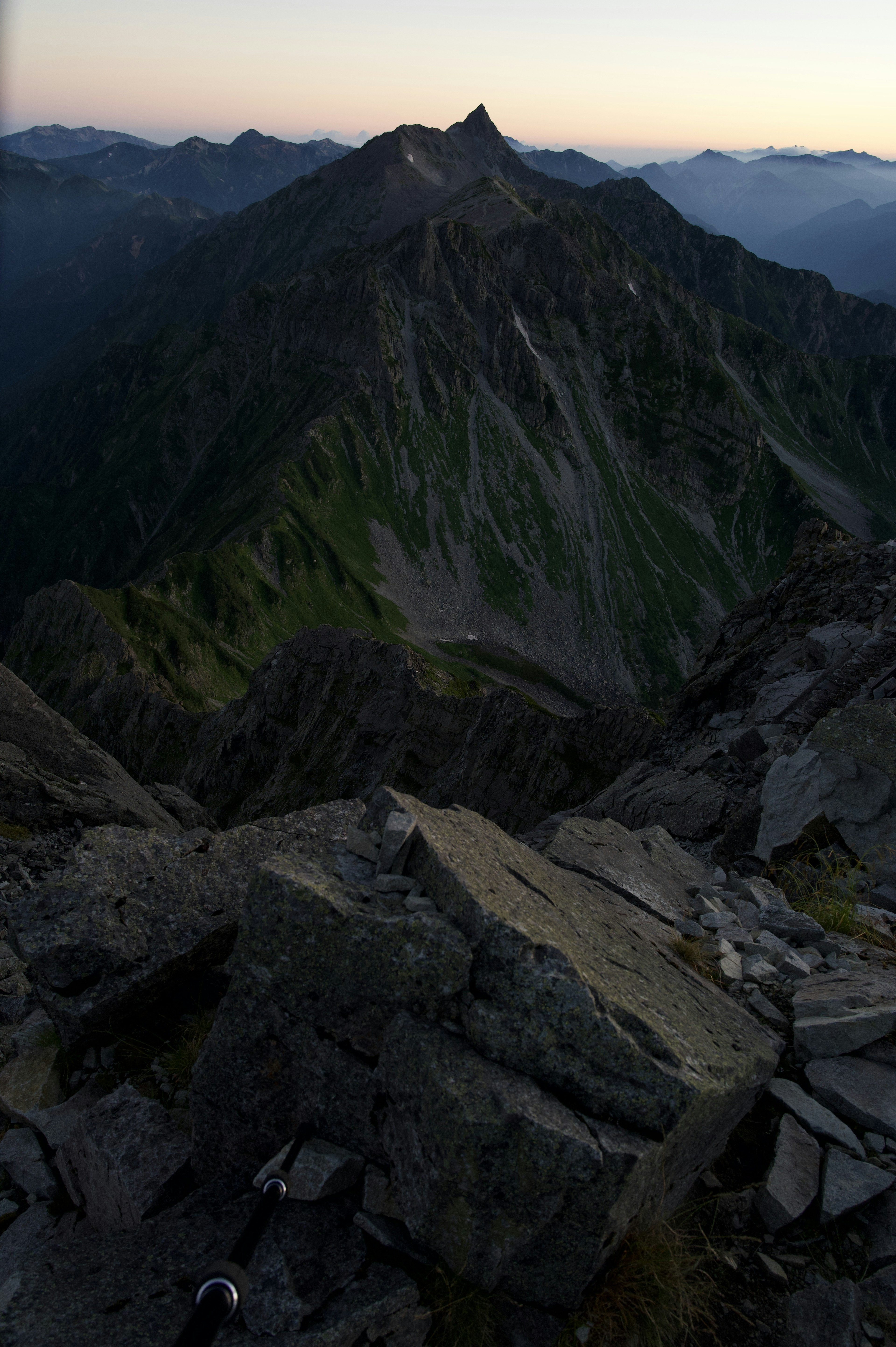 Vue depuis le sommet de la montagne montrant des rochers et des pentes verdoyantes