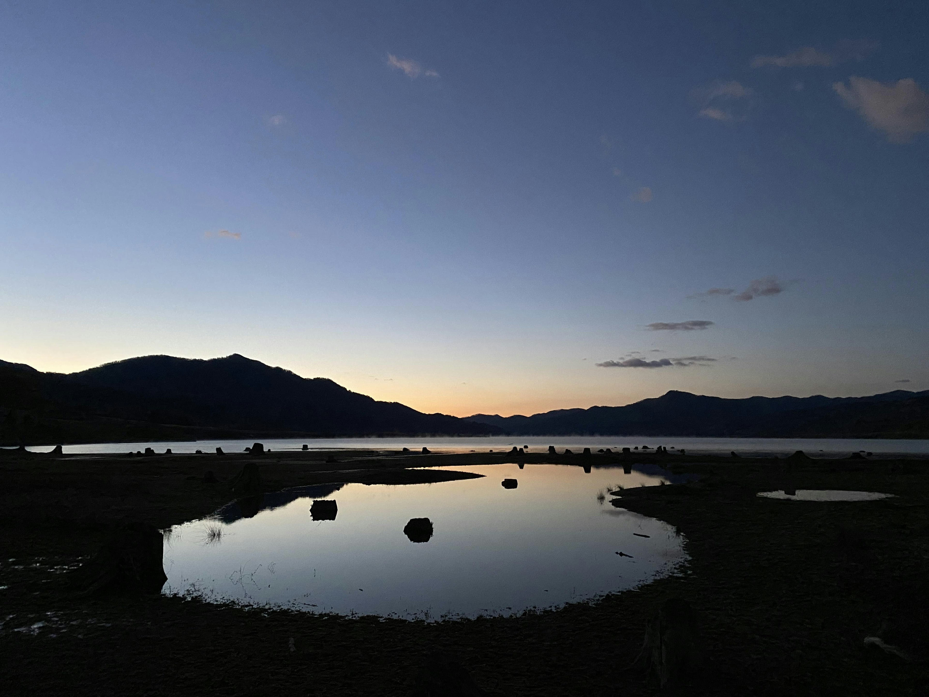 Paisaje tranquilo de la tarde de un lago con siluetas de montañas