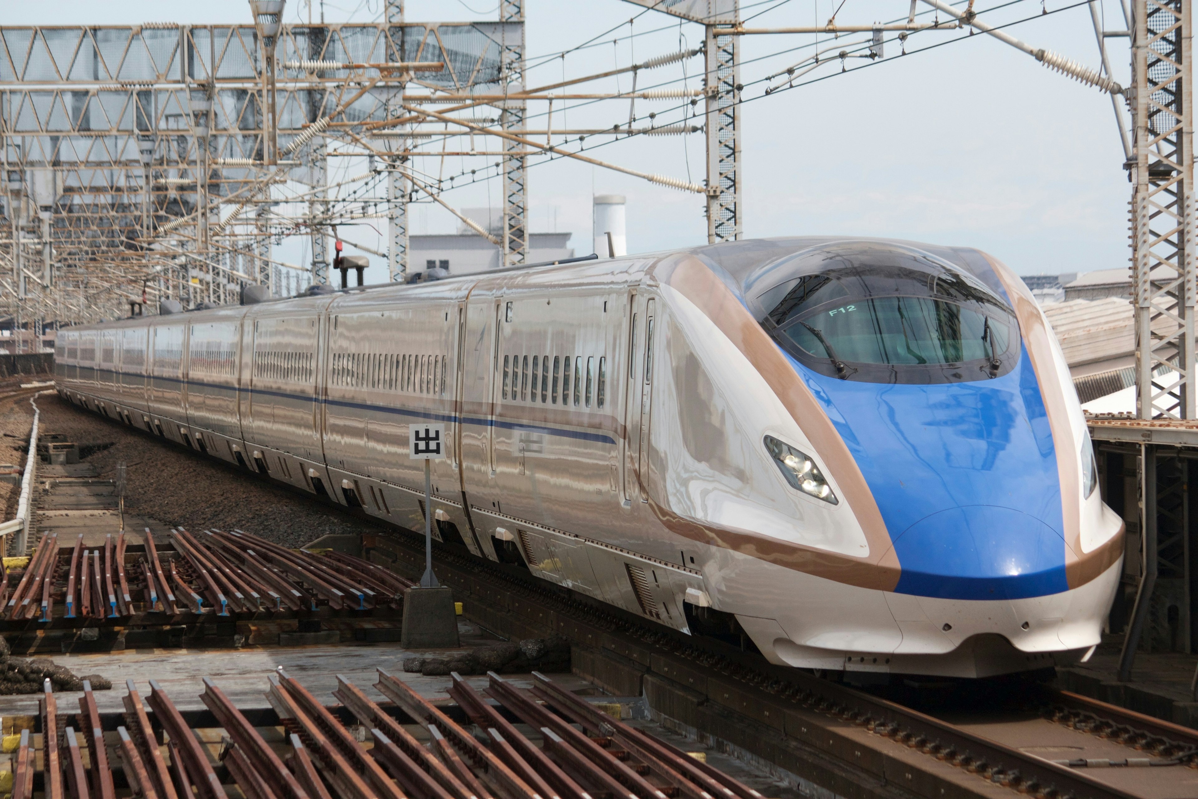 Shinkansen with a distinctive blue section traveling on the tracks